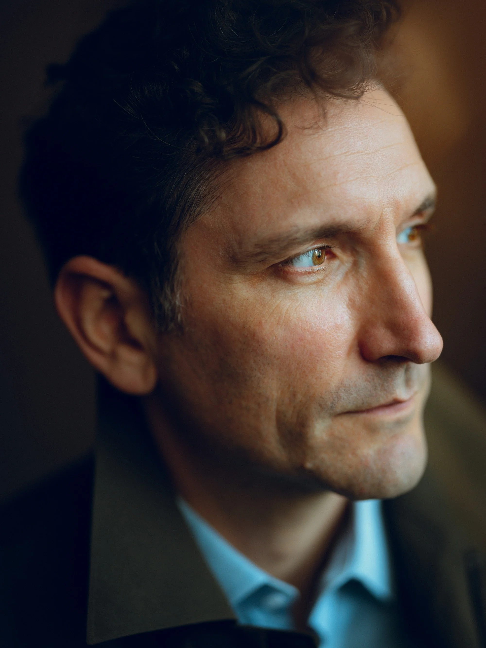 Close-up of a man's face showing his profile, with focused expression and short, dark curly hair.