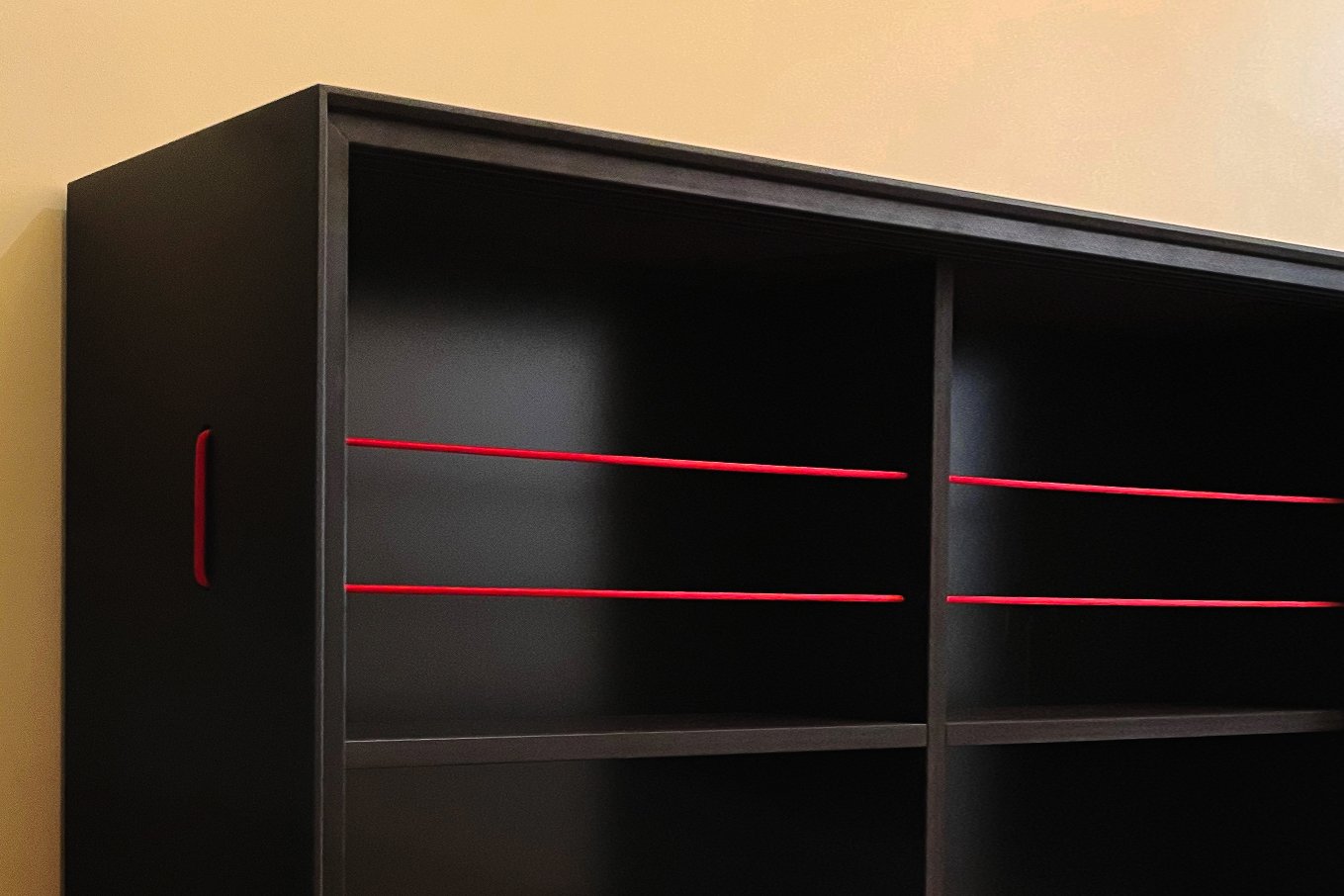 Nahaufnahme Innenfächer hängendes Schuhregal aus schwarzem MDF, rote elastische Bänder zur Schuhhalterung quer durch die Fächer gespannt