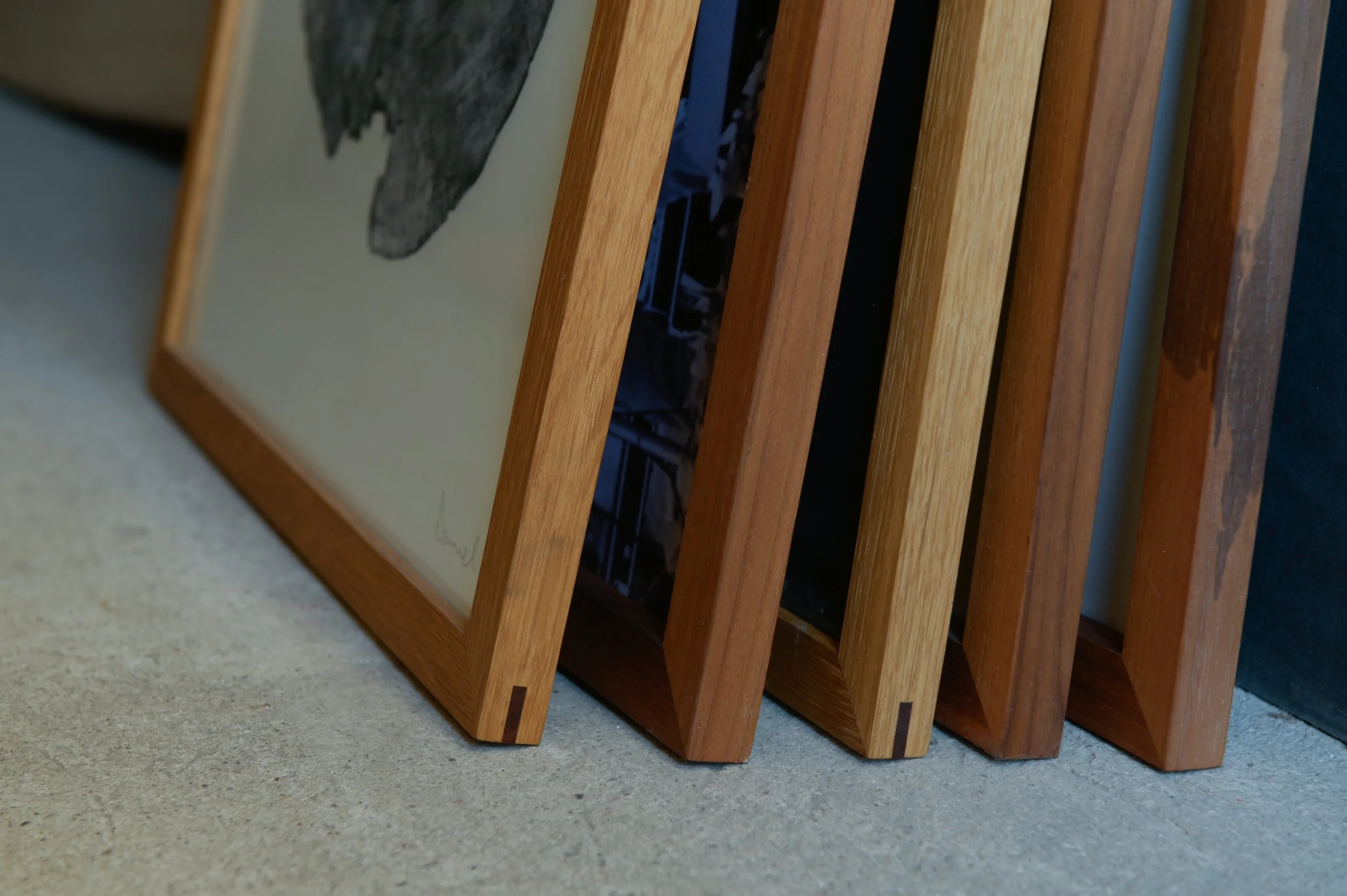 Eckverbindungen verschiedener Holzbilderrahmen aus Nussbaum, Eiche und Kirsche mit Fremdfeder