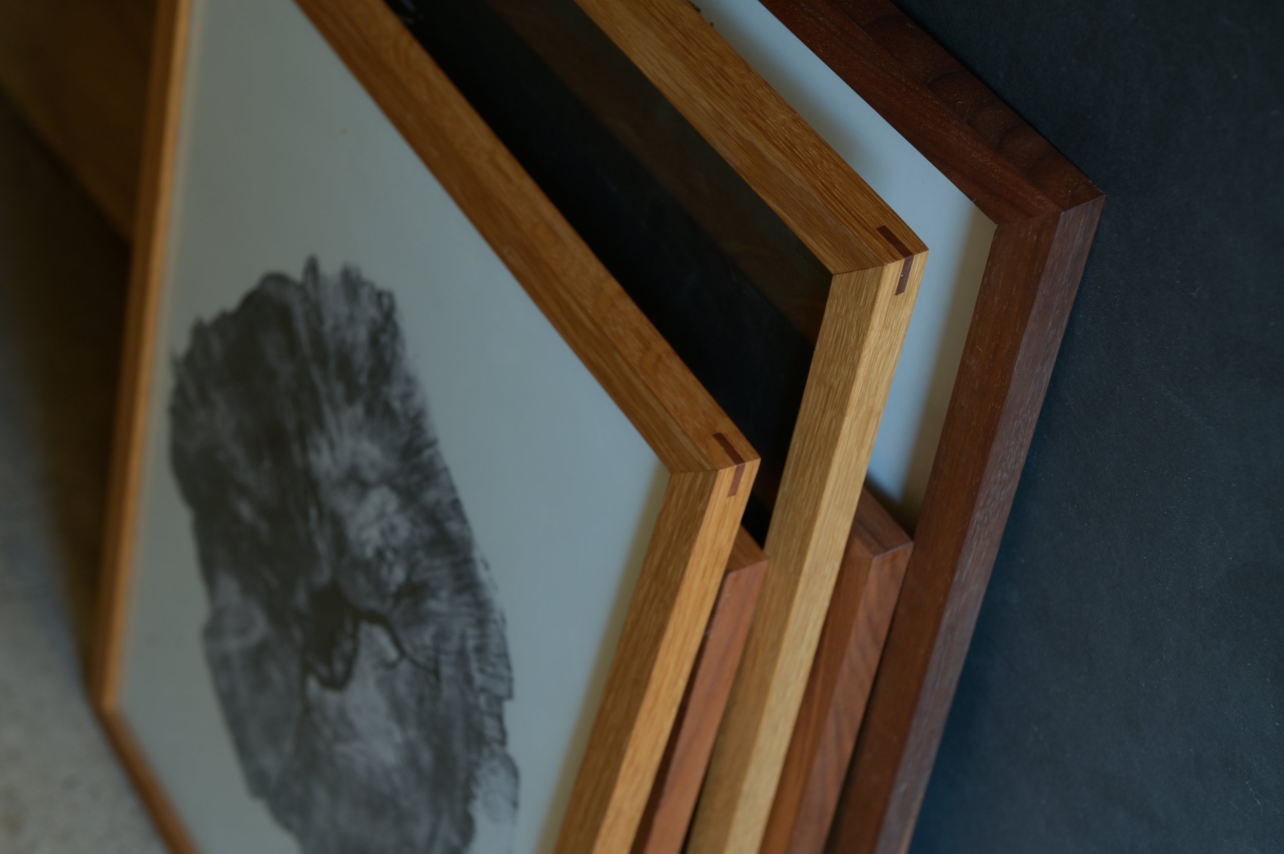 Detailaufnahme mehrerer Holzbilderrahmen aus Nussbaum, Eiche und Kirsche mit geölter Oberfläche