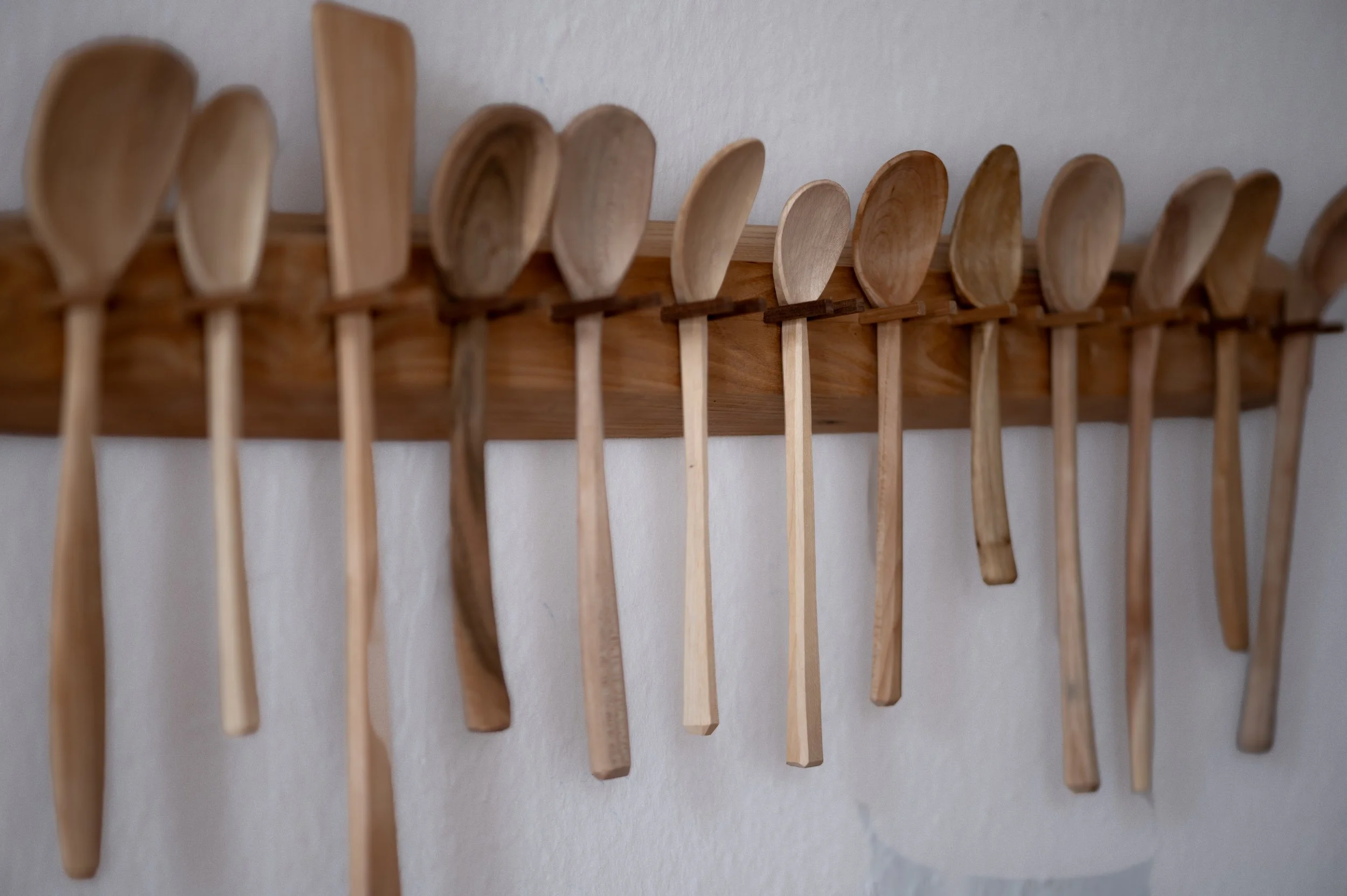 Verschiedene handgeschnitzte Holzlöffel auf Wandleiste