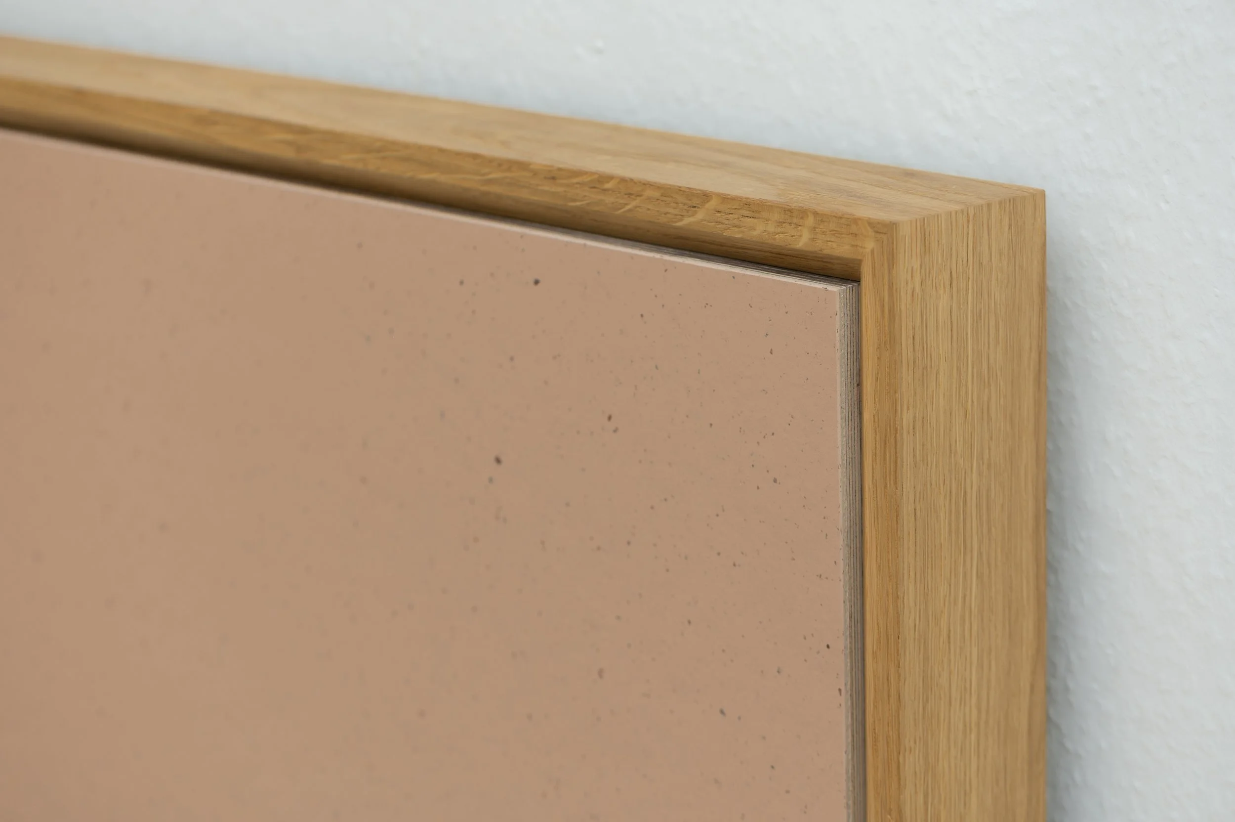 Eckdetail Kopfteil von Holzbett aus Eiche auf Gehrung mit eingelegter Linoleum-Füllung in Altrosa, sichtbare Holzmaserung