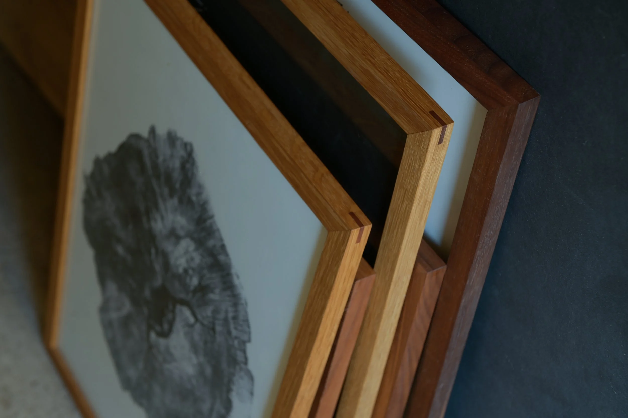 Detailaufnahme mehrerer Holzbilderrahmen aus Nussbaum, Eiche und Kirsche mit geölter Oberfläche