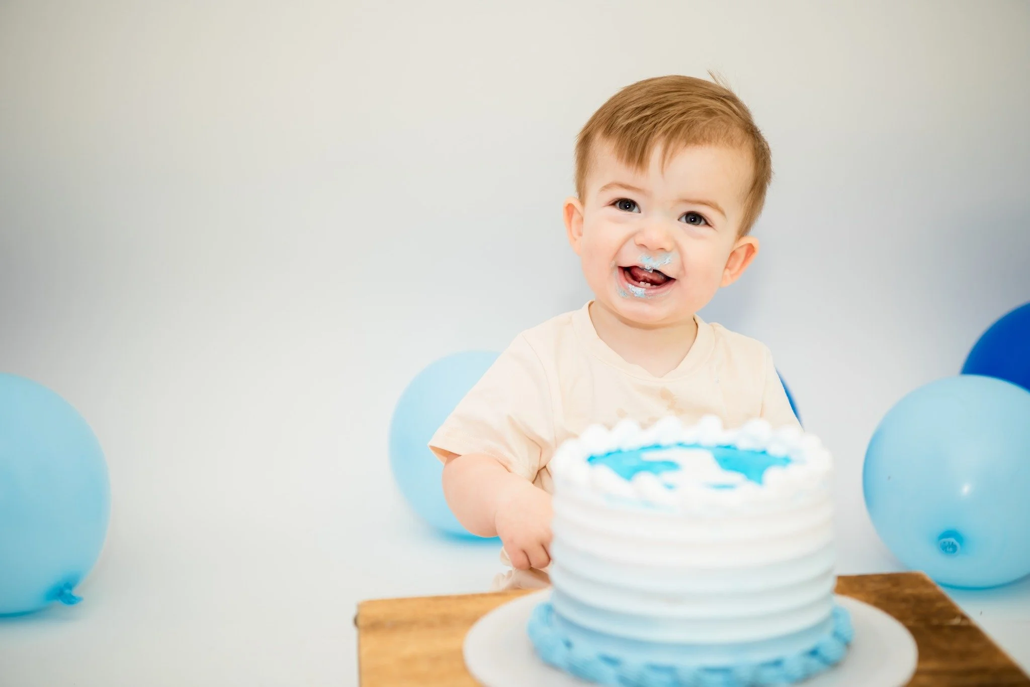 A young boy with a birthday cake, surrounded by blue balloons, celebrating his birthday.