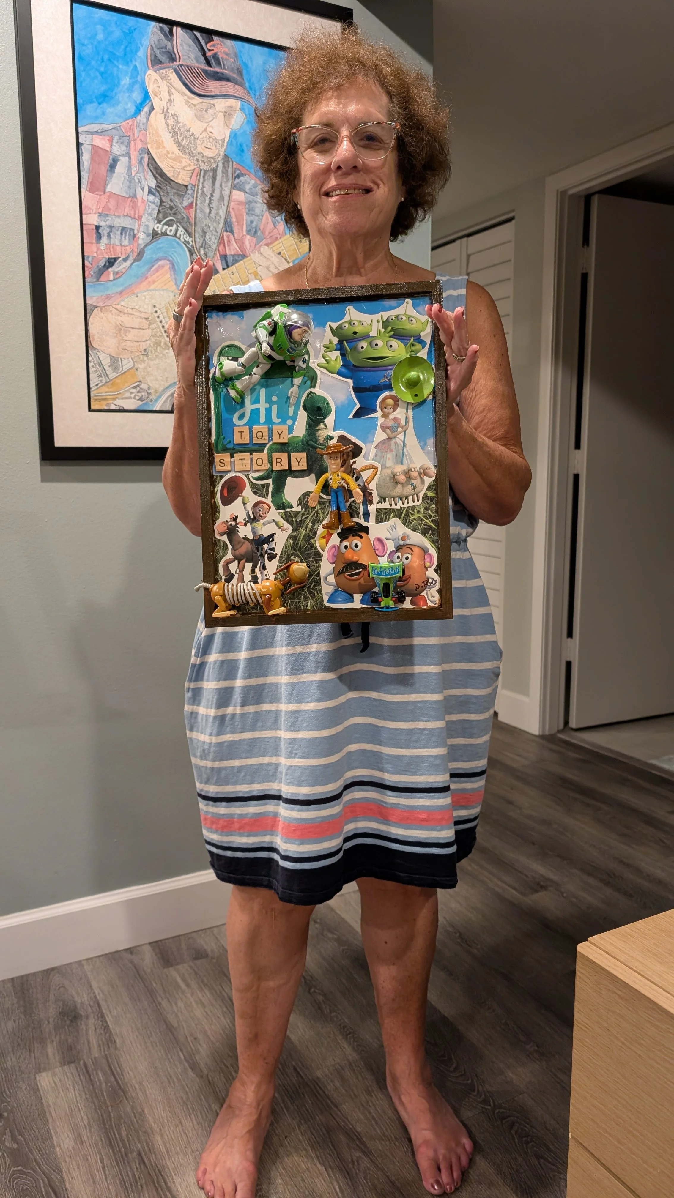 Sarasota artist Debra Rich holding her Toy Story assemblage artwork