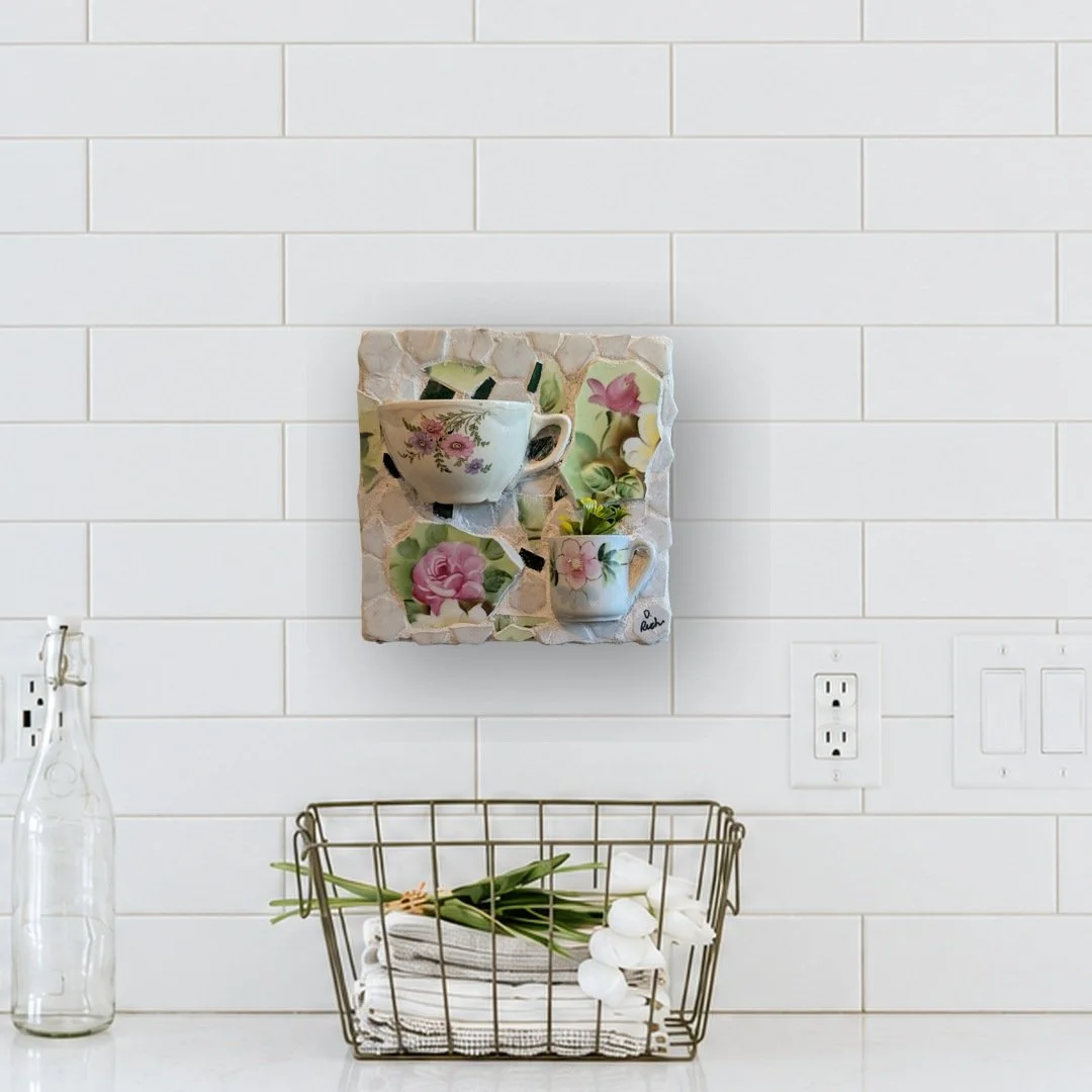 Cups of Joy mosaic wall art with two floral cups set in green china, hung on a white subway tile kitchen wall
