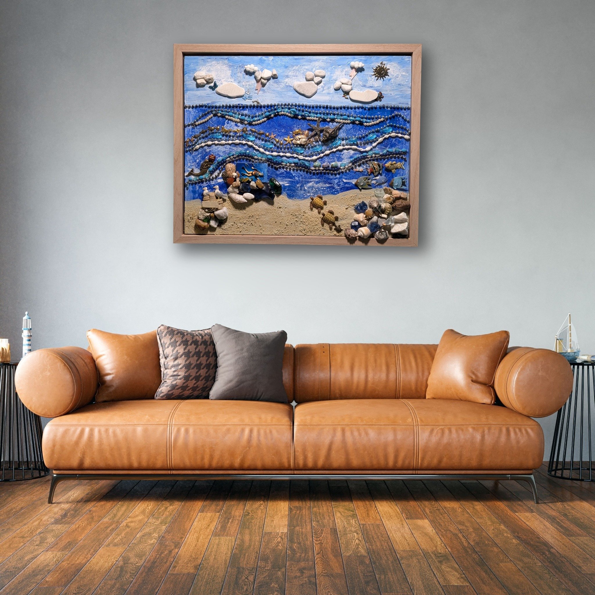 Handcrafted 22x18 inch beach assemblage made with natural shells, stones, and beads in a seaside scene, by Debra Rich posed in a living room