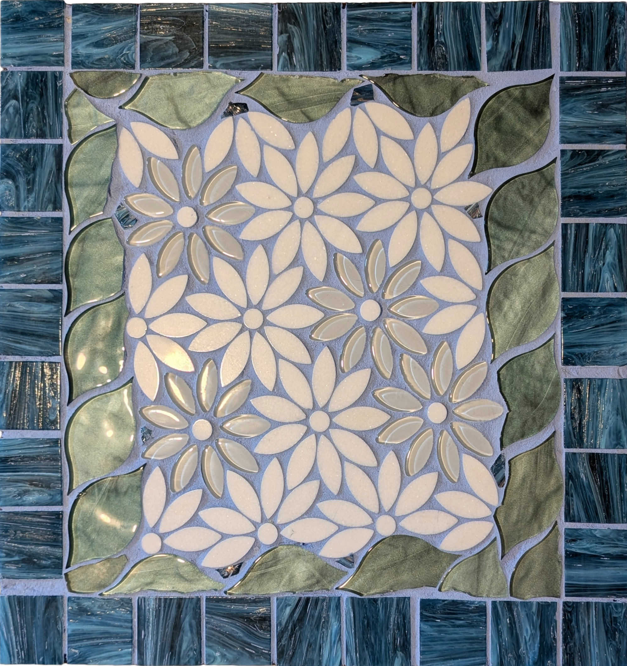 Handcrafted mosaic table depicting a field of daisies surround by blue and green tiles-top