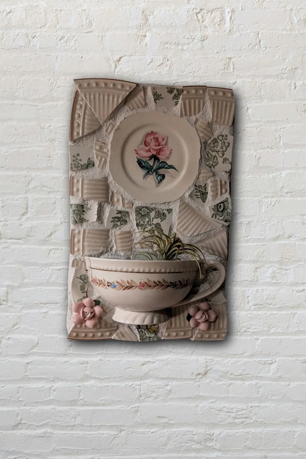 Vintage cup and rose plate mosaic wall art on white brick — handcrafted broken china assemblage by Debra Rich
