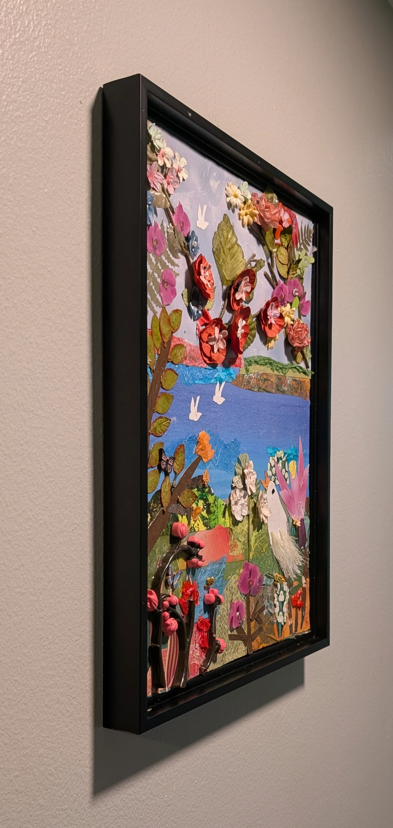 Textured mixed-media collage depicting a vibrant landscape with bright 3D paper flowers, water, & flying white birds -left side, by Sarasota Artist Debra Rich.