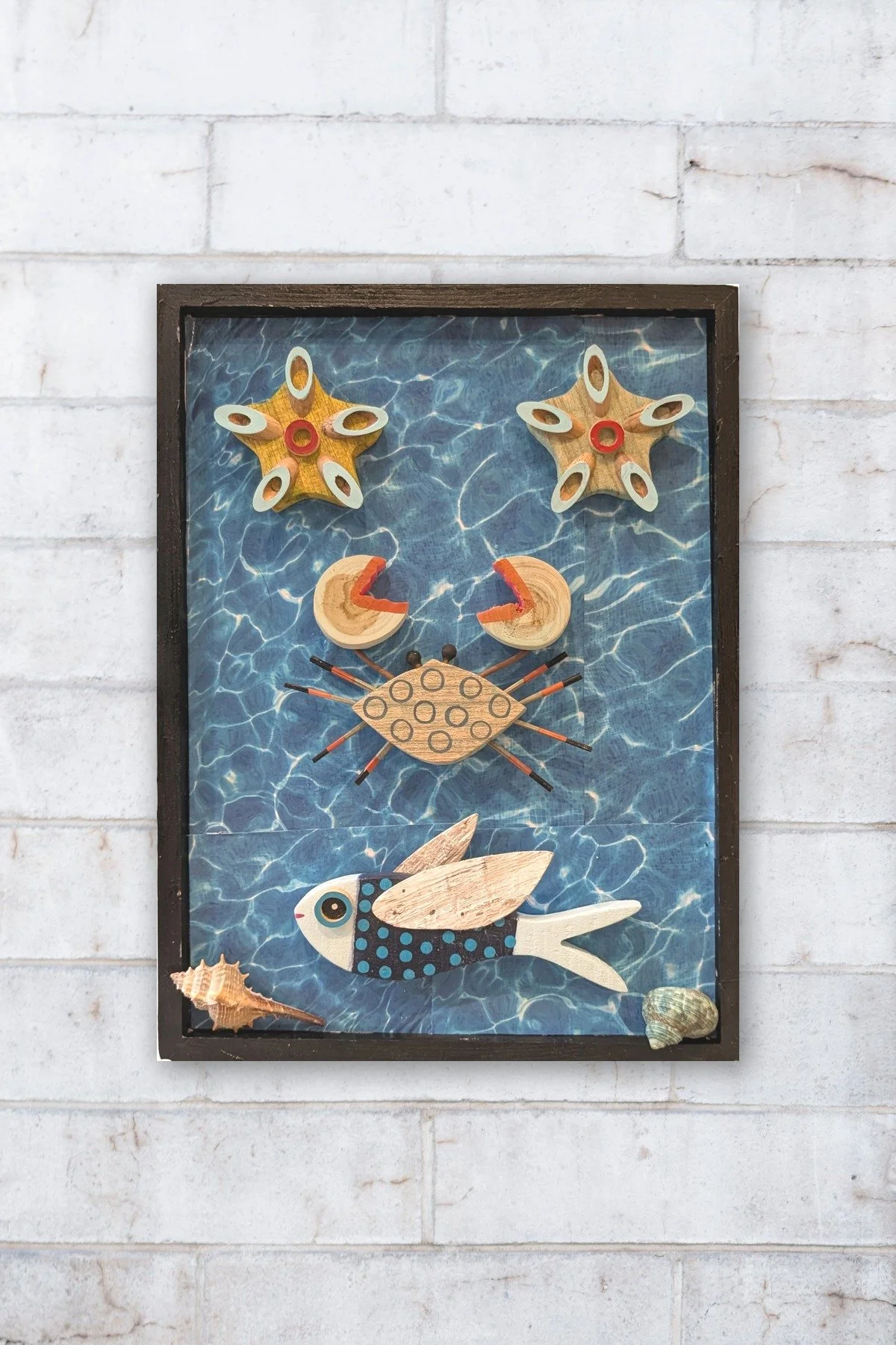 A Fish Tale assemblage by Debra Rich hanging on a white brick wall