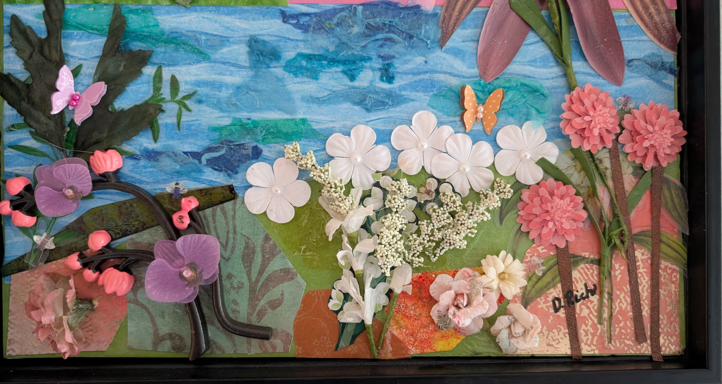 Detail of found-object flower garden in Mango's Last Stand — white daisies, pink dahlias, purple orchids, paper butterflies, by Debra Rich
