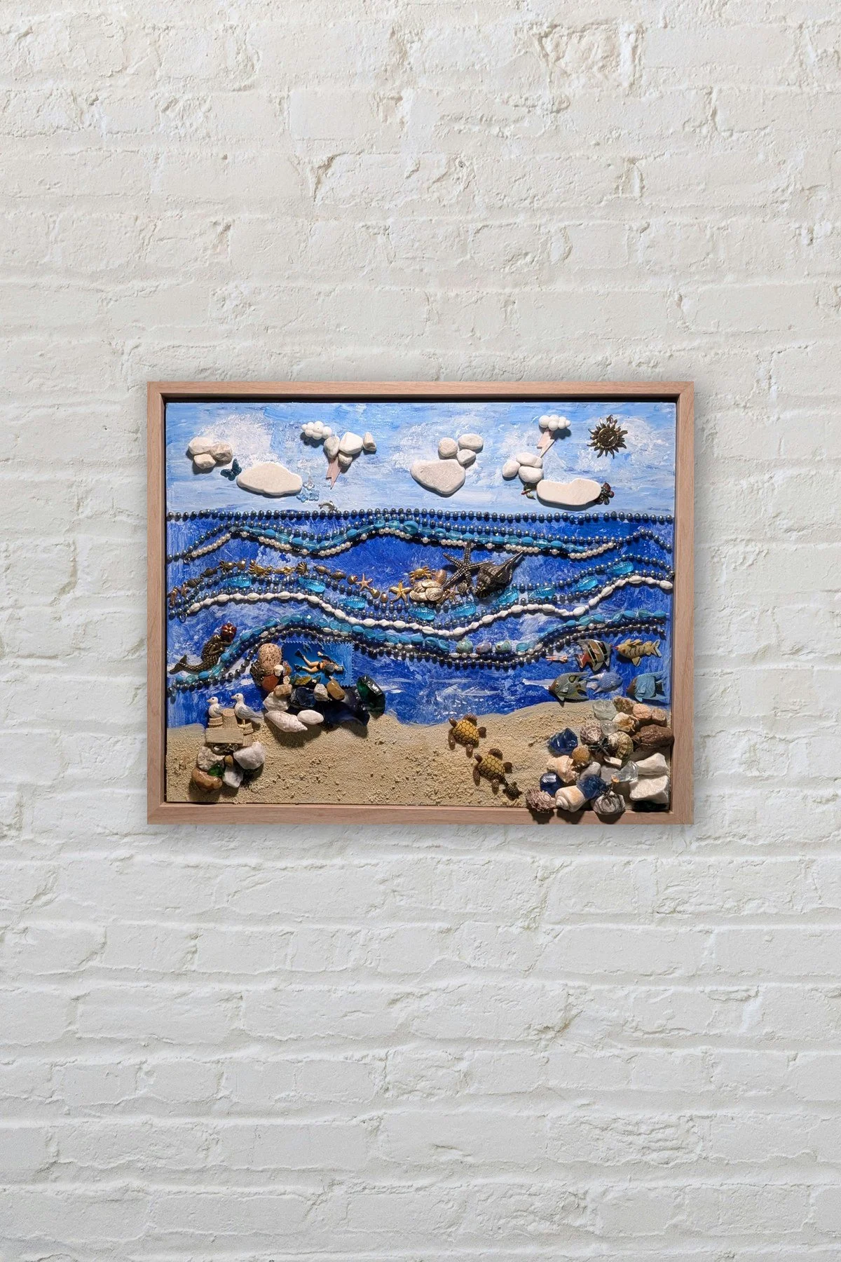 Coastal Harmony Turtle Beach assemblage art by Debra Rich on a white brick wall