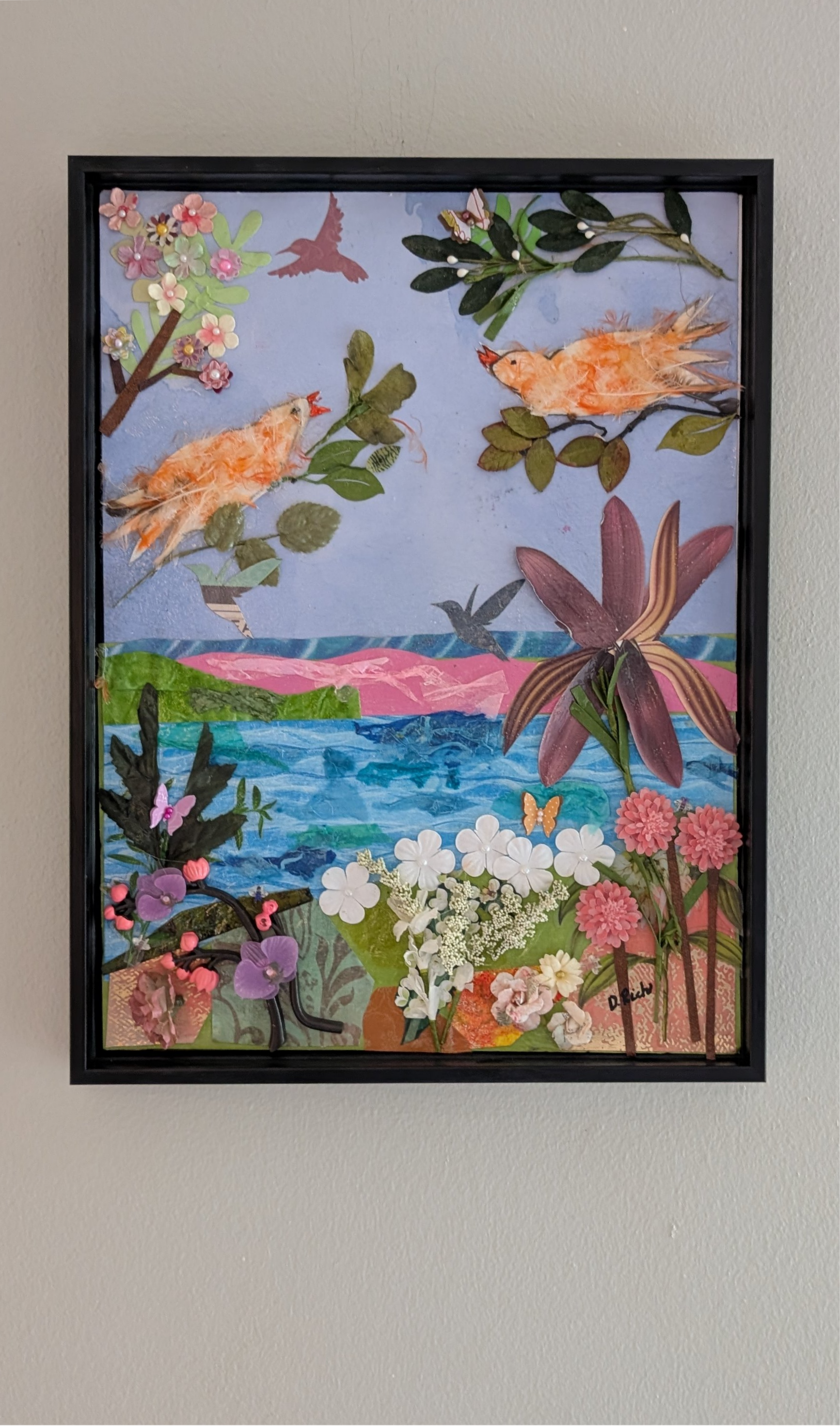 Mango's Last Stand framed mixed-media collage hanging on wall, two feather canaries in paper landscape with found-object flowers, by Debra Rich Sarasota