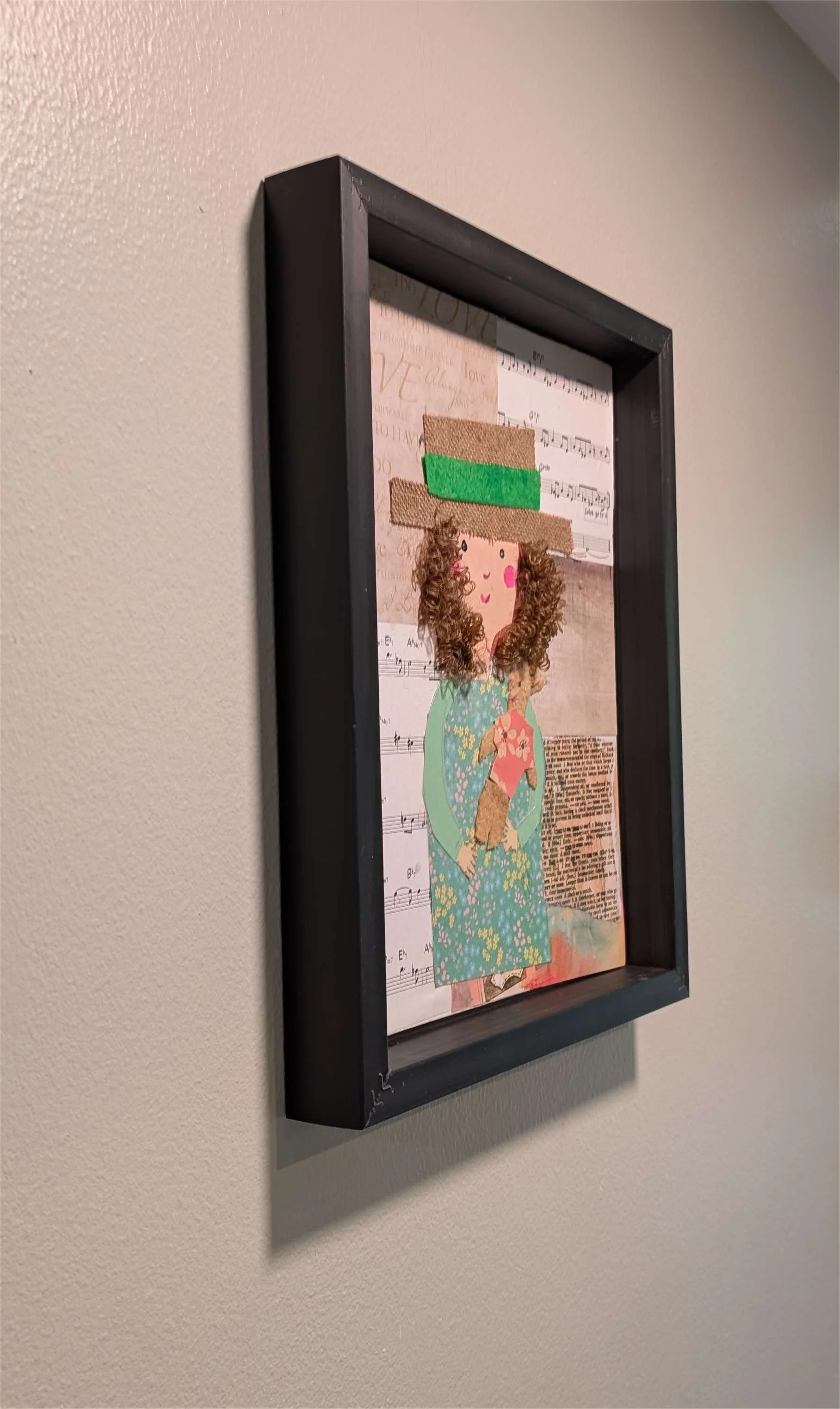 Textured mixed-media collage depicting a young girl with curly hair, with a hat on, holding her stuffed animal surrounded by sheet music-left-wall, by Sarasota Artist Debra Rich.