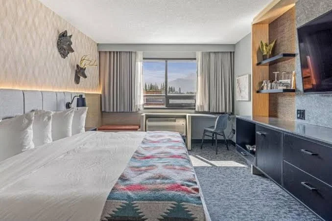 A guest room at Everwild in Canmore, with a king bed and a window looking toward the mountains