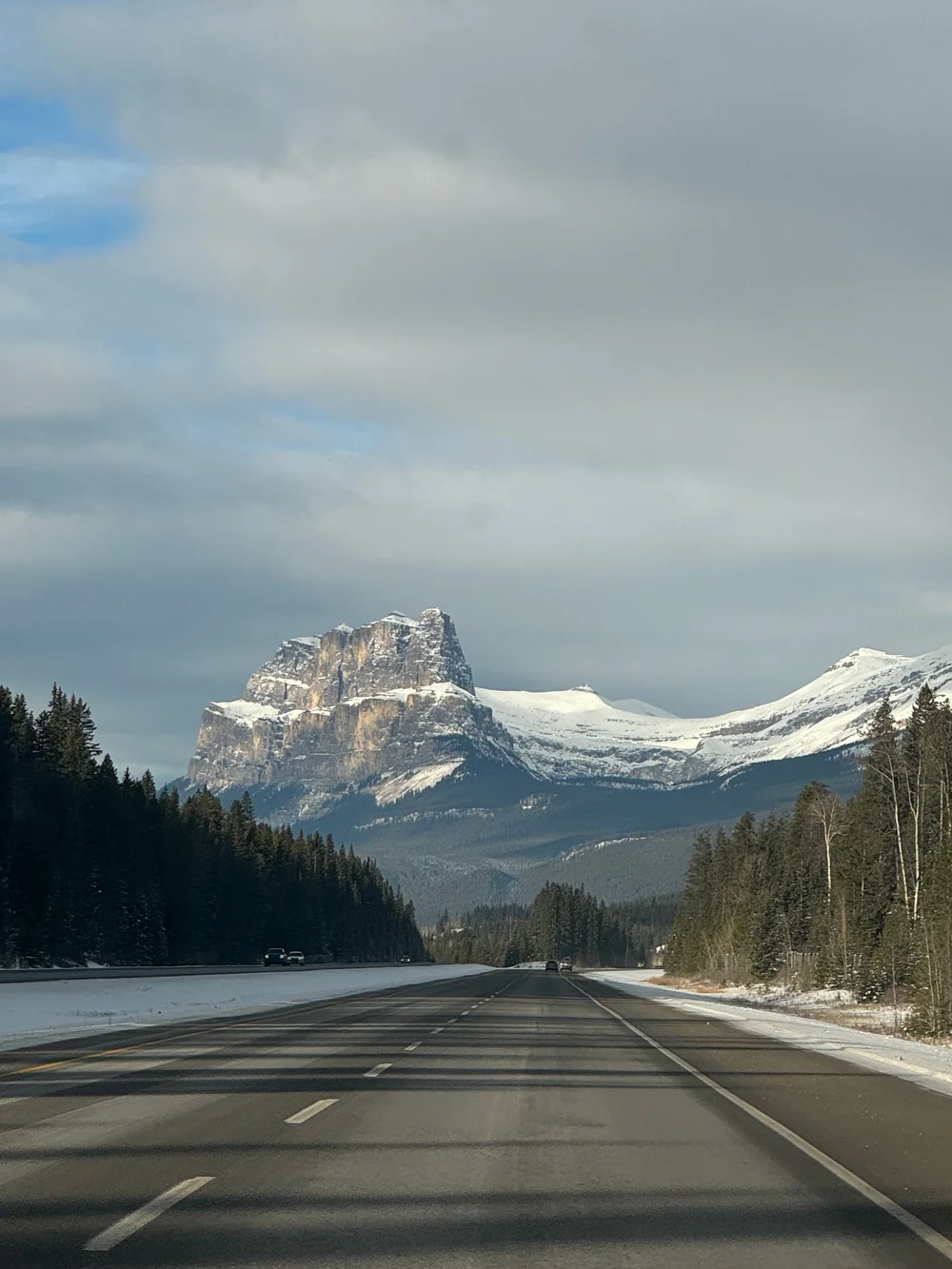 Winter transfer to Banff: snow-dusted Rocky Mountain beside a quiet highway