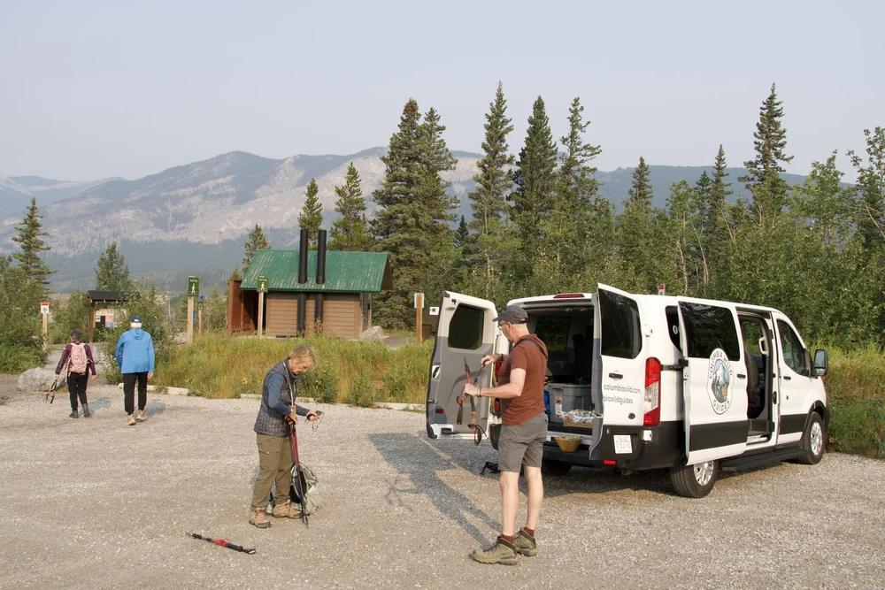 A Columbia Wild Guides van at a trailhead parking area in the Canadian Rockies