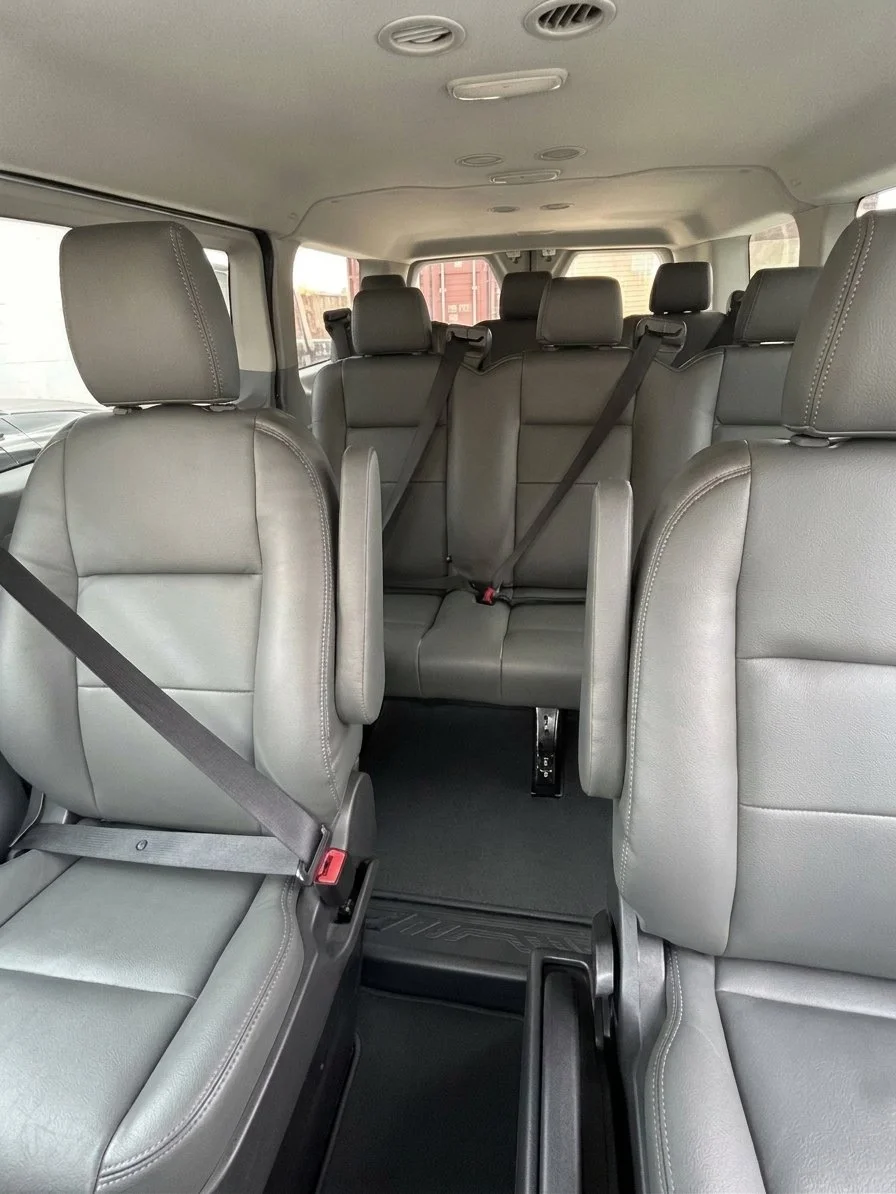 Interior of a Ford Transit passenger van with grey seats and seatbelts, used for private Calgary Airport to Banff transfers