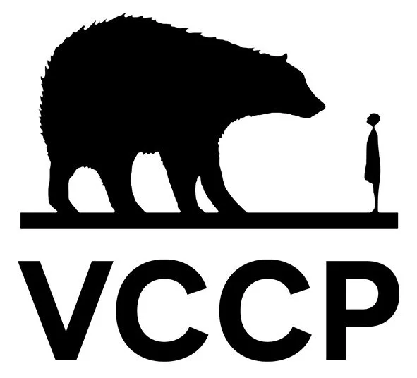 Silhouette of a person standing in front of a bear, with the acronym "VCCP" below.