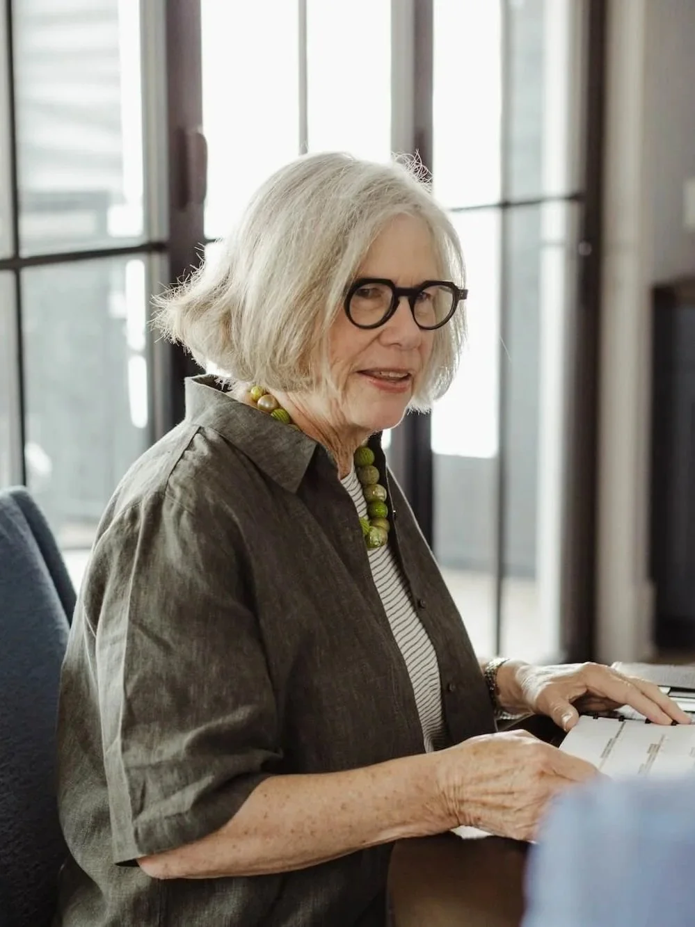 A woman sits at a conference table at Grey Dunes to discuss her family office.