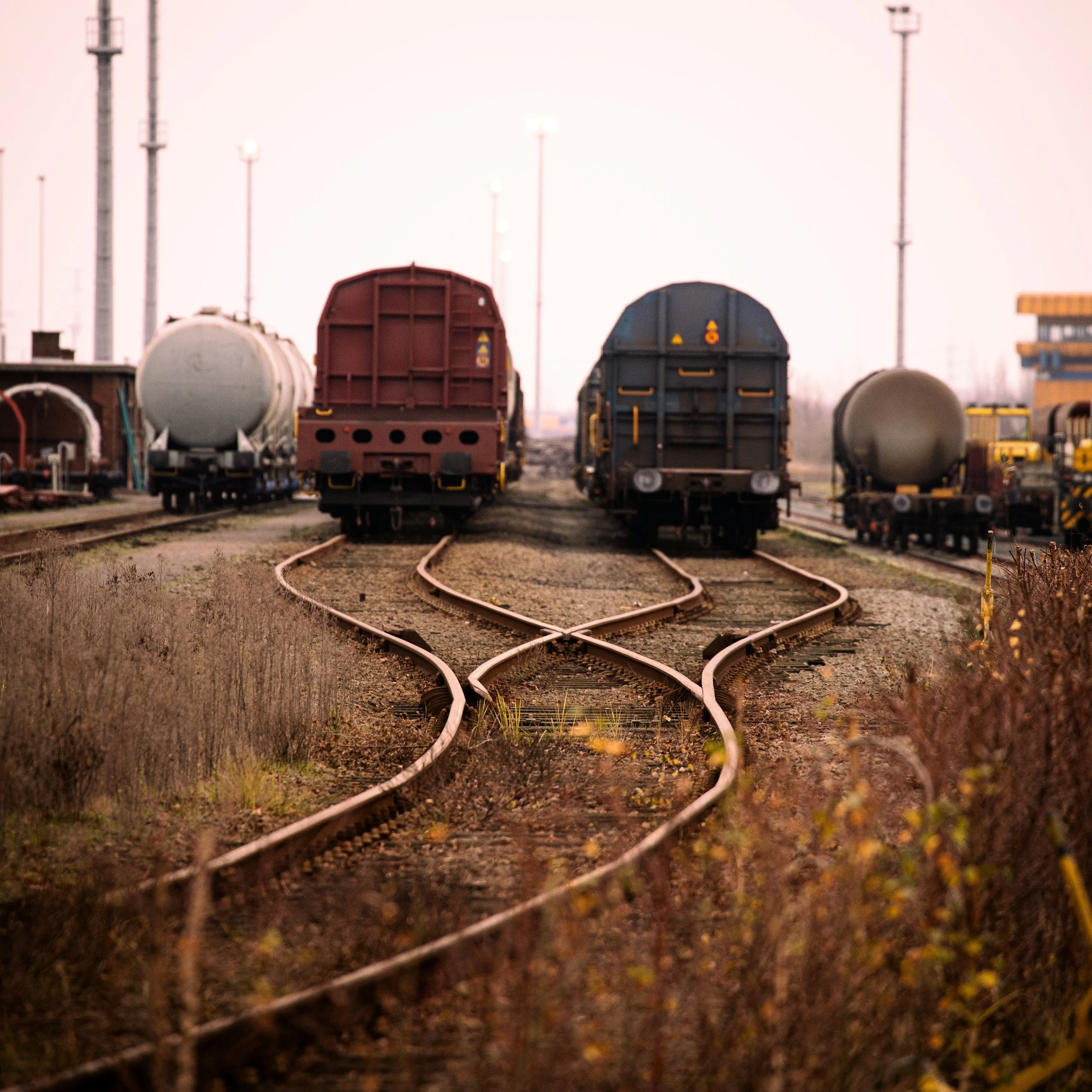 two trains in a trainyard side by side at rest on tracks