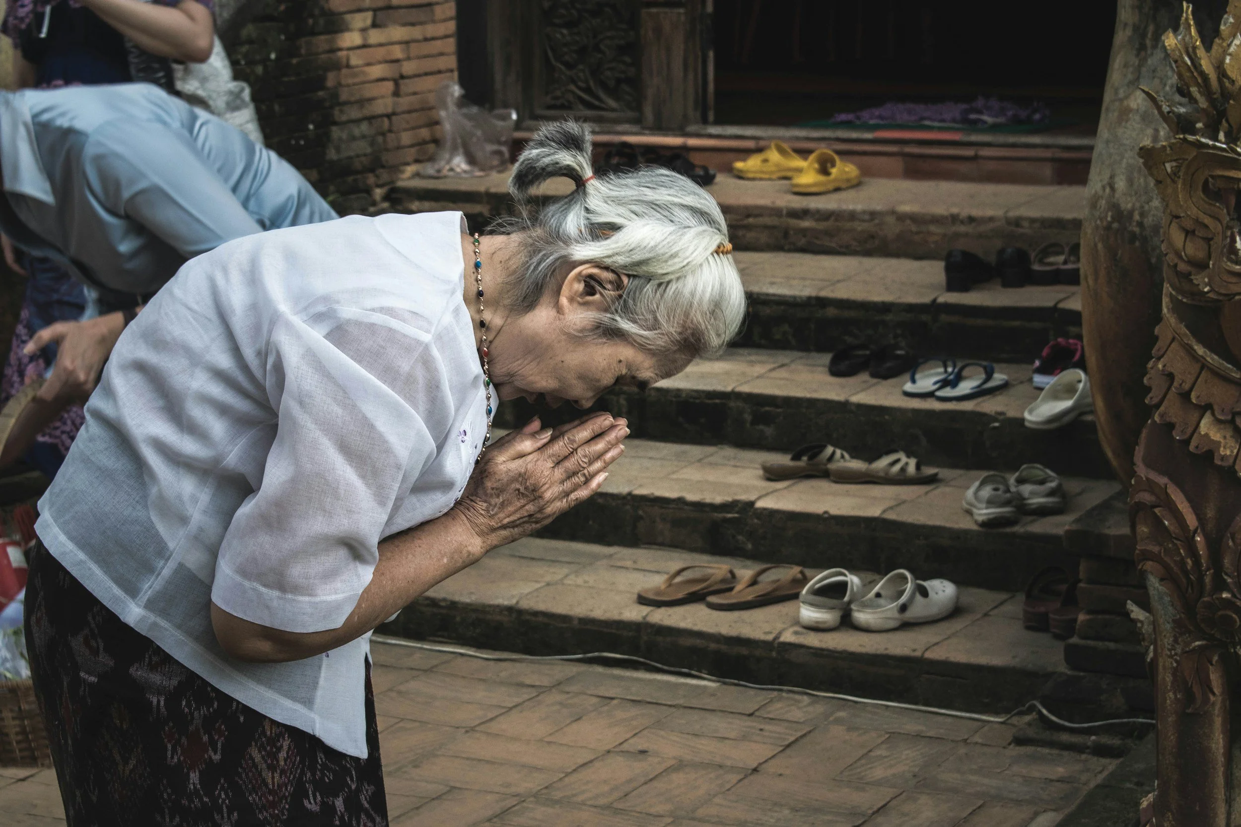 Elderly Asian woman bows in prayer