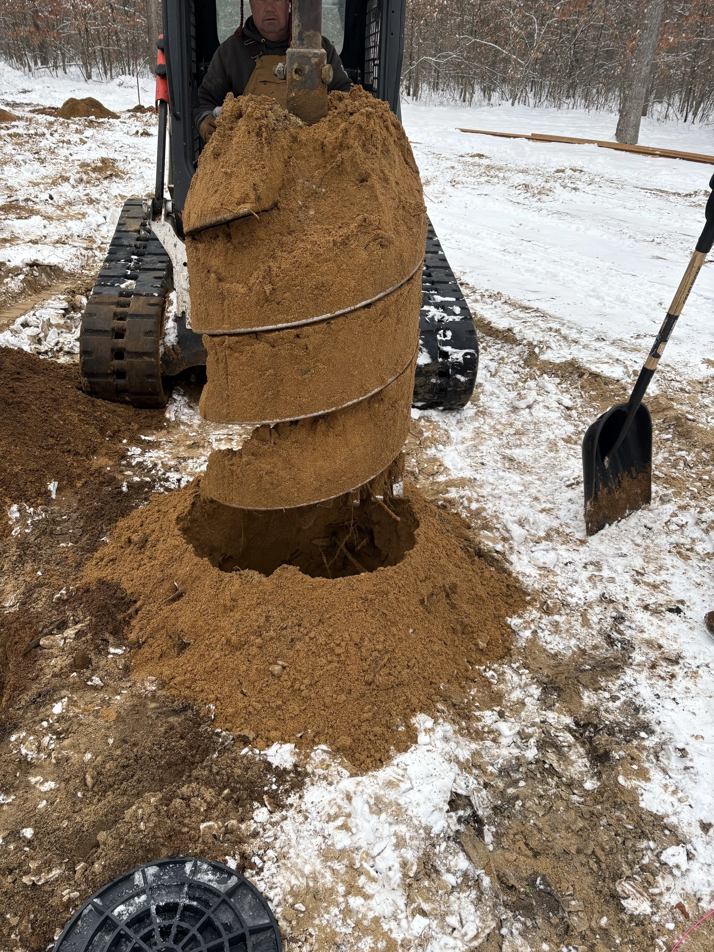 A person using its auger to drill into the ground.