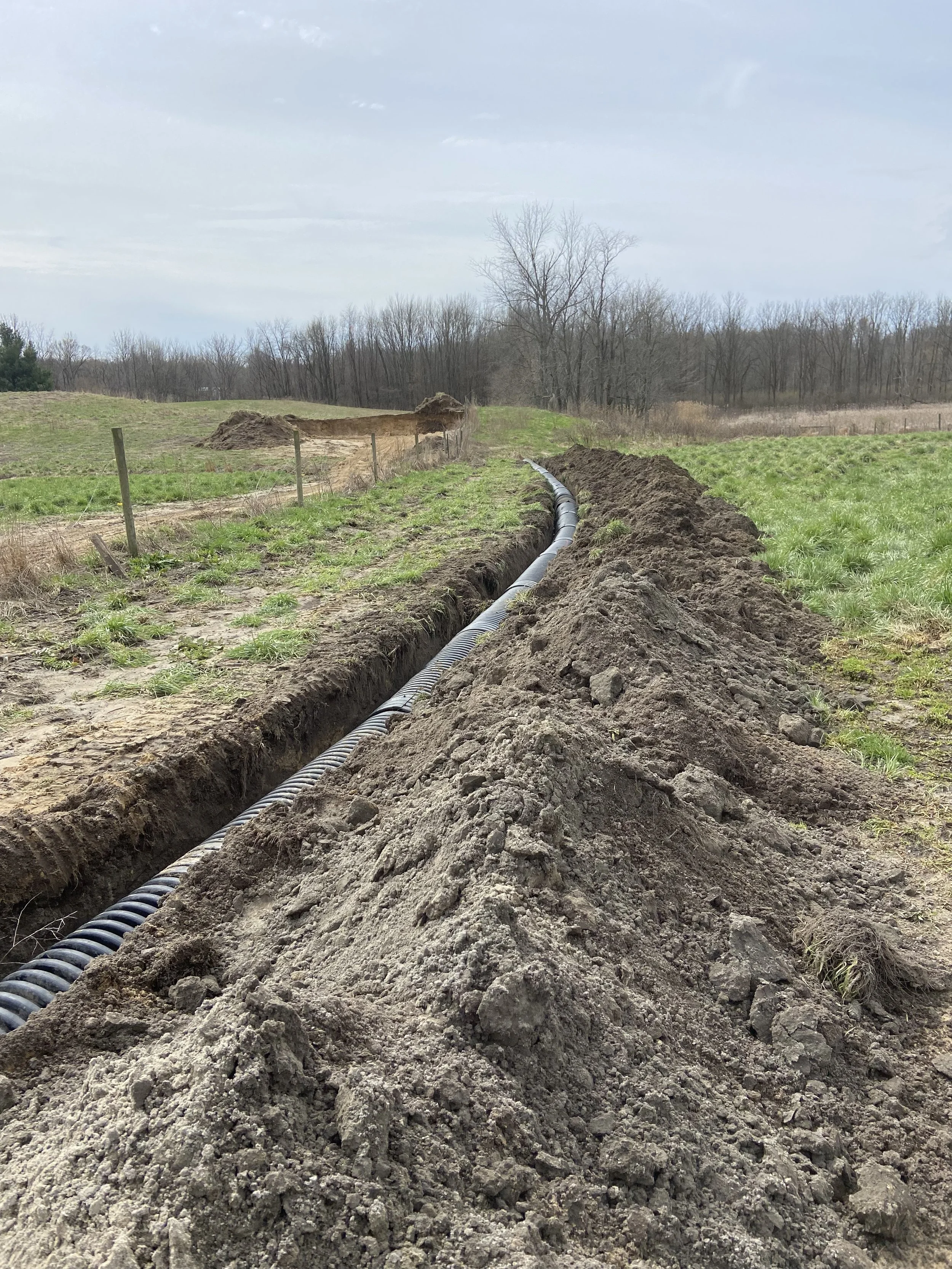 A pipe laid in a trench in a rural field