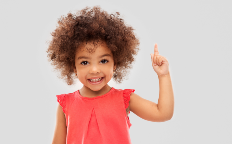 Smiling young girl pointing upward, representing curiosity and imaginative thinking.