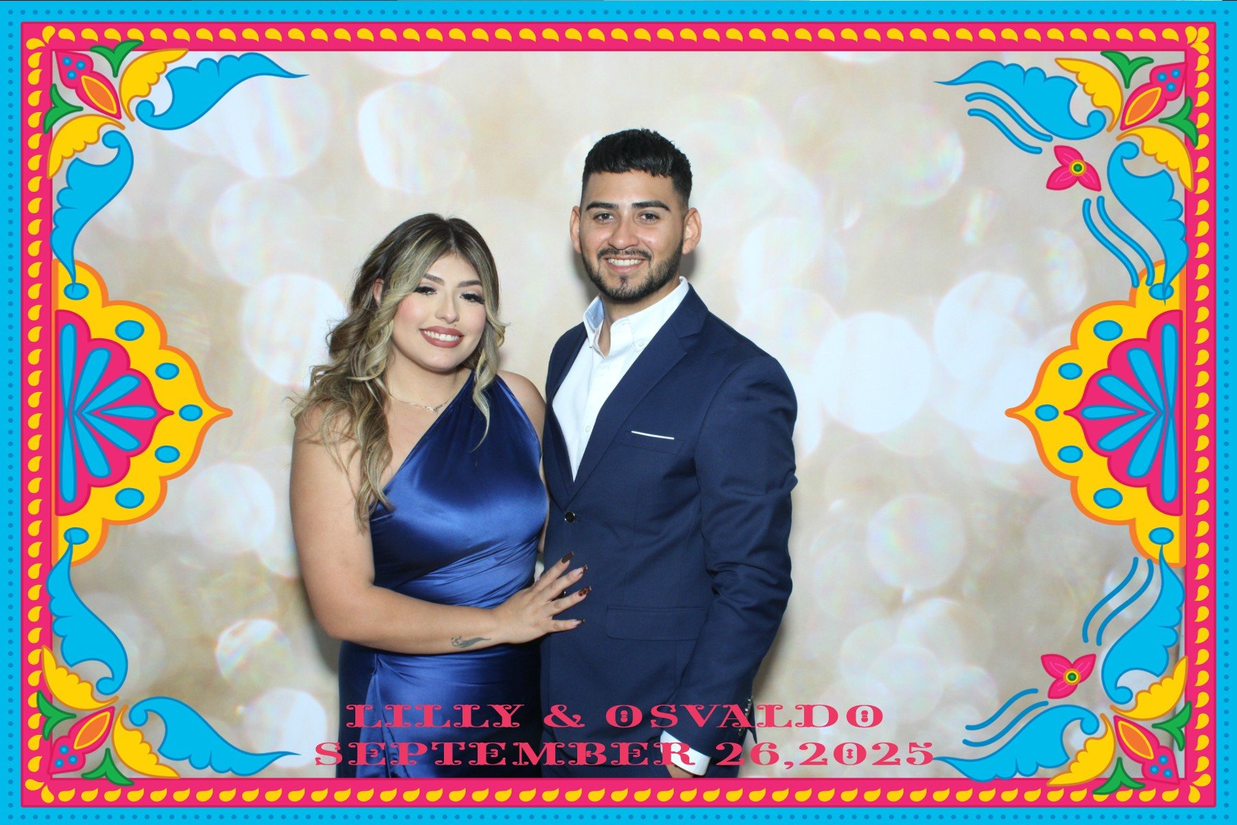 A couple dressed in formal attire smiling at the camera at an event with colorful borders and the text "Lilly & Osvaldo September 26, 2025" at the bottom.