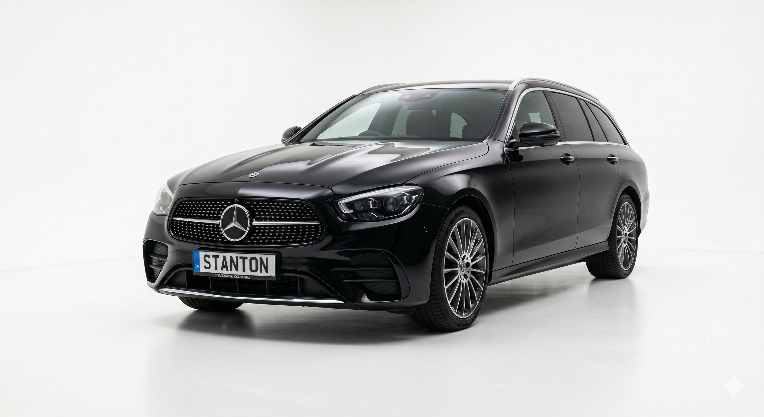 A black Mercedes-Benz station wagon with a custom license plate that reads "STANTON" is displayed against a plain white background. Offering an executive travel feel.