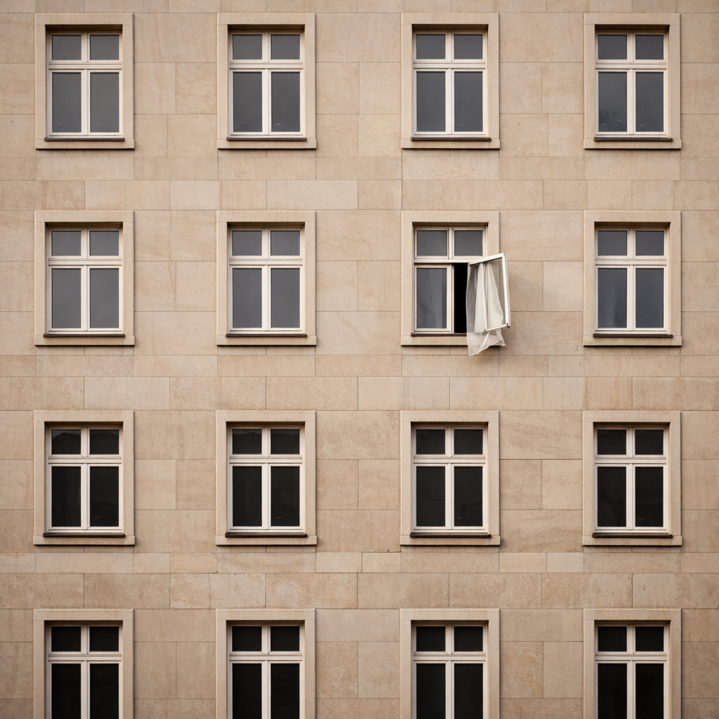 Beige building facade with repeating windows, one window open