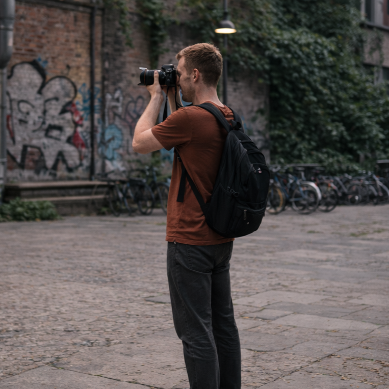 Photographer working calmly outdoors with a deliberate pause before taking the next shot