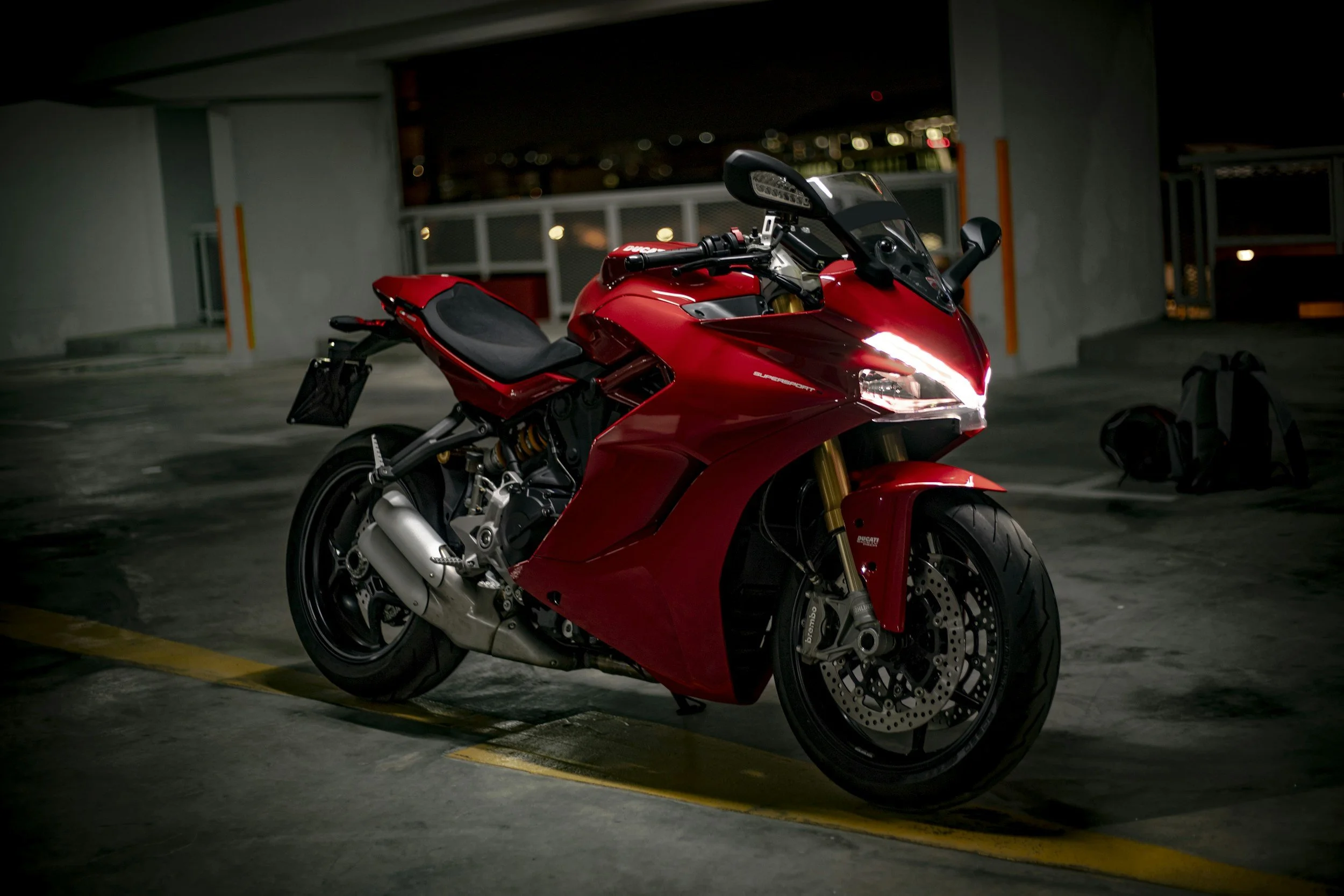 Red sport motorcycle parked in a dimly lit parking garage at night.