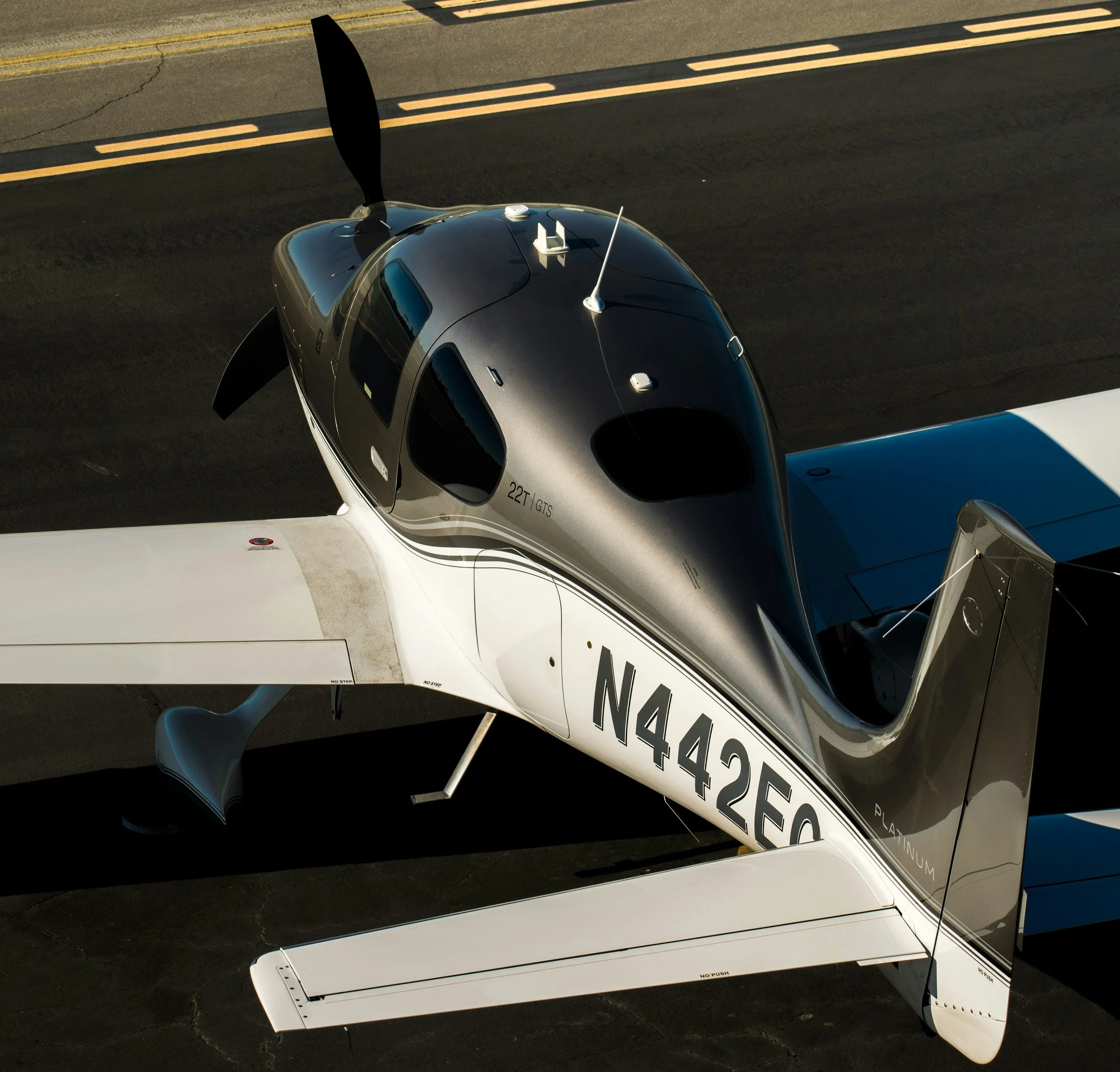 Front view of a vintage black and silver airplane inside an aircraft hangar, with other aircraft visible in the background.