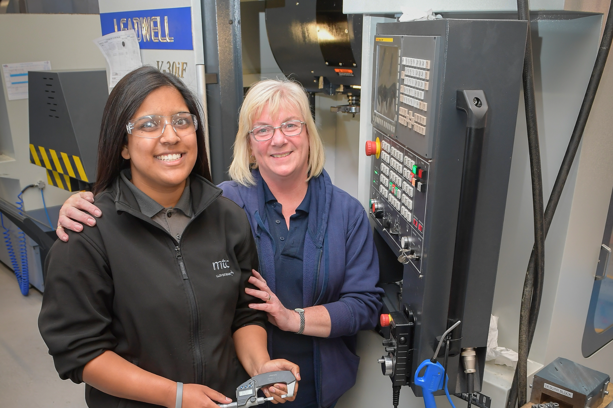 An ASG team member and apprentice in front of machinery