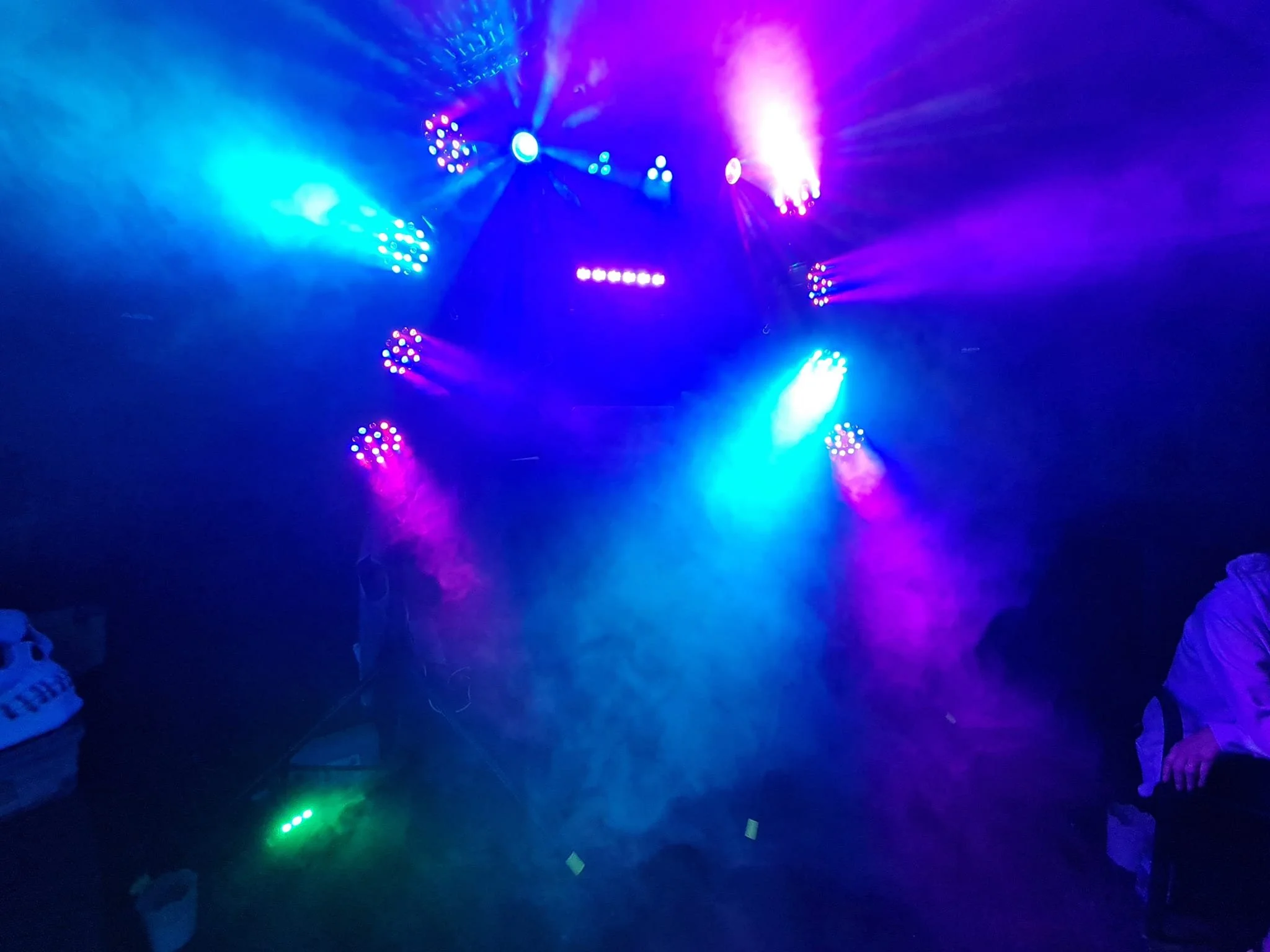 Colorful stage lighting with blue, purple, pink, and green lights illuminating a dark room, creating a vibrant atmosphere.