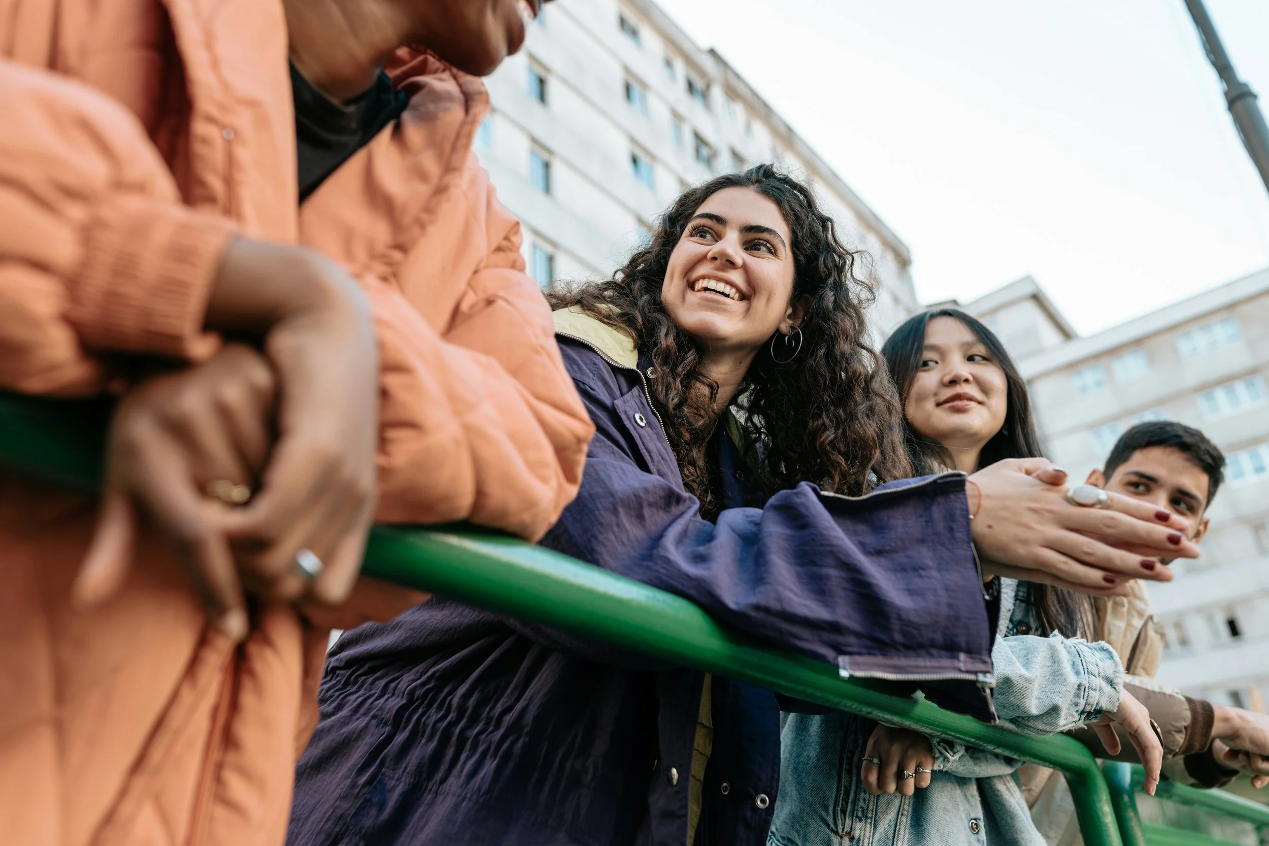 Four people leaning over a railing joyfully engaging in a conversation
