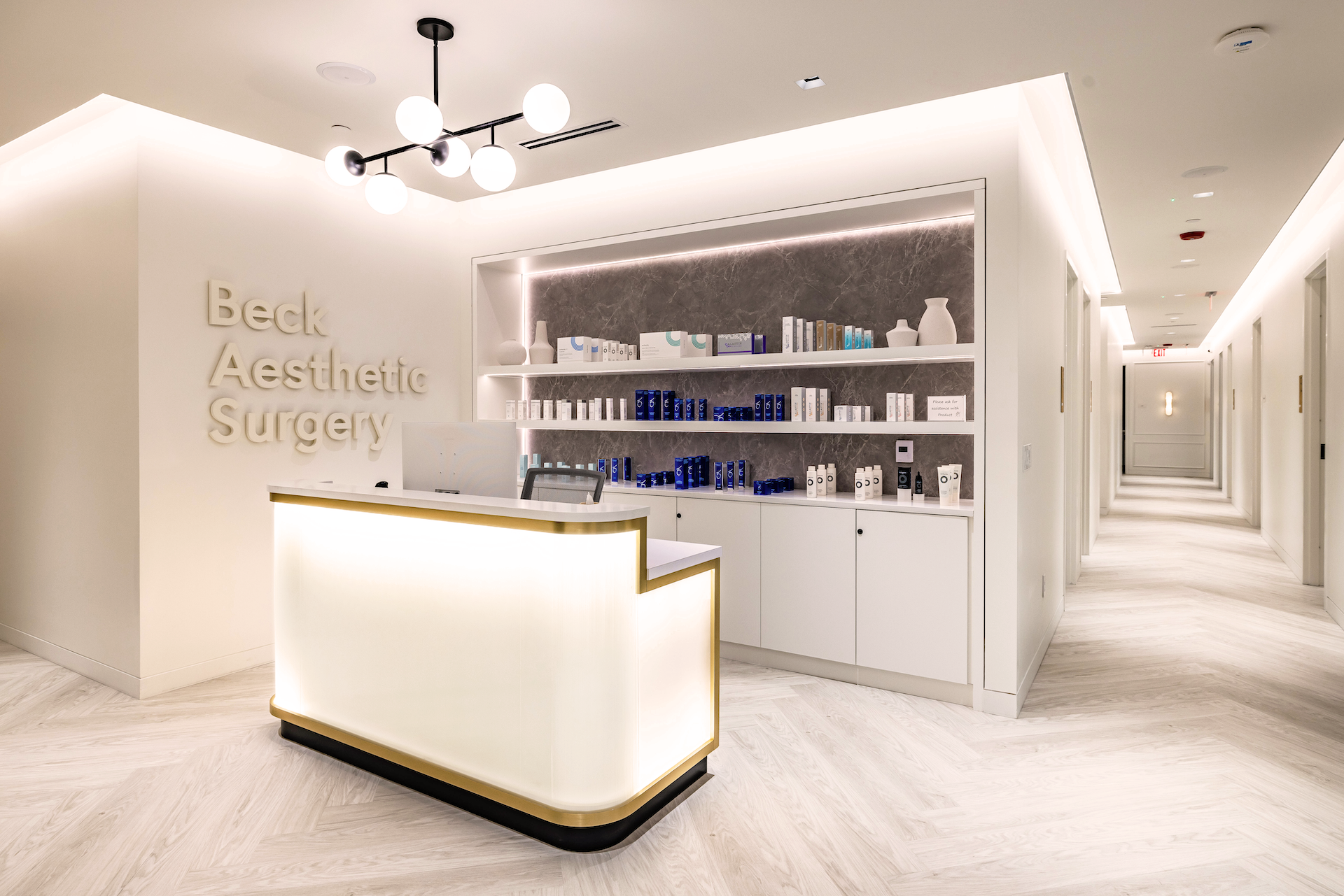 A warm inviting glowing check-out desk with illumnaited display shelving and creamy painted walls.