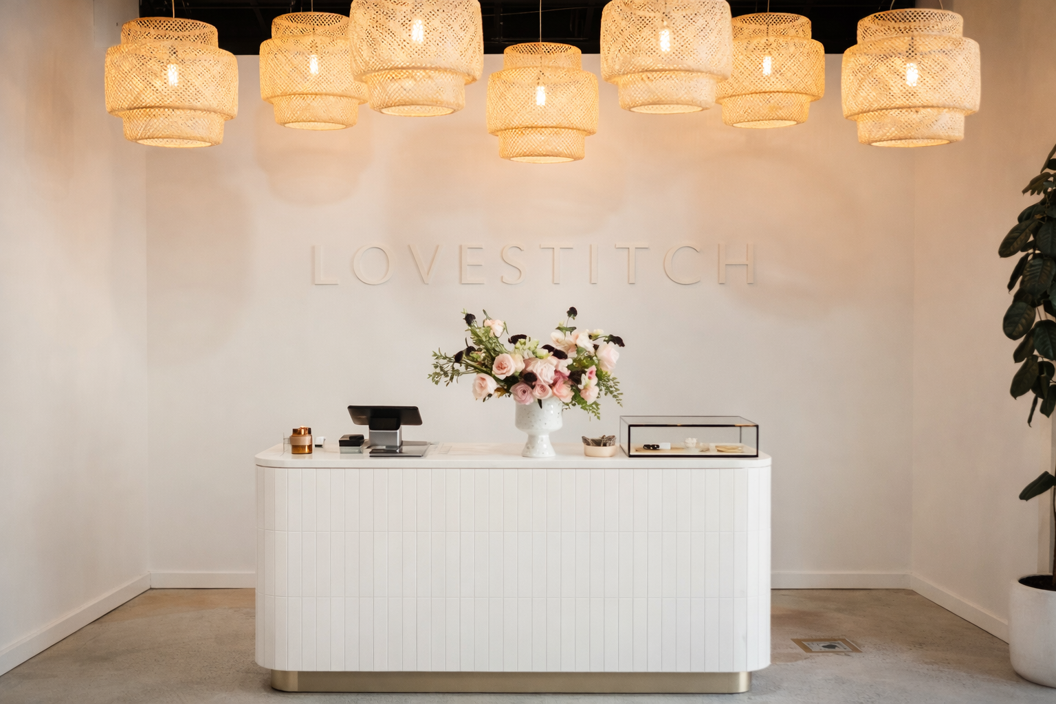 A monochromatic white on white retail cashwrap with brand accent wall and natural pendant lights