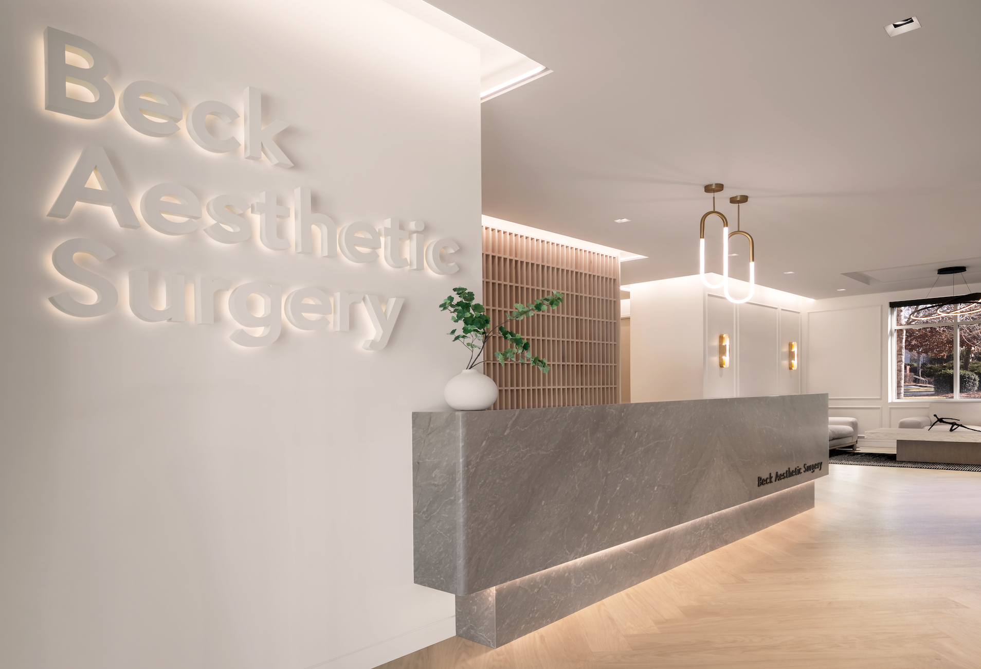 A hotel inspired marble reception desk and brand wall at a doctor's office.