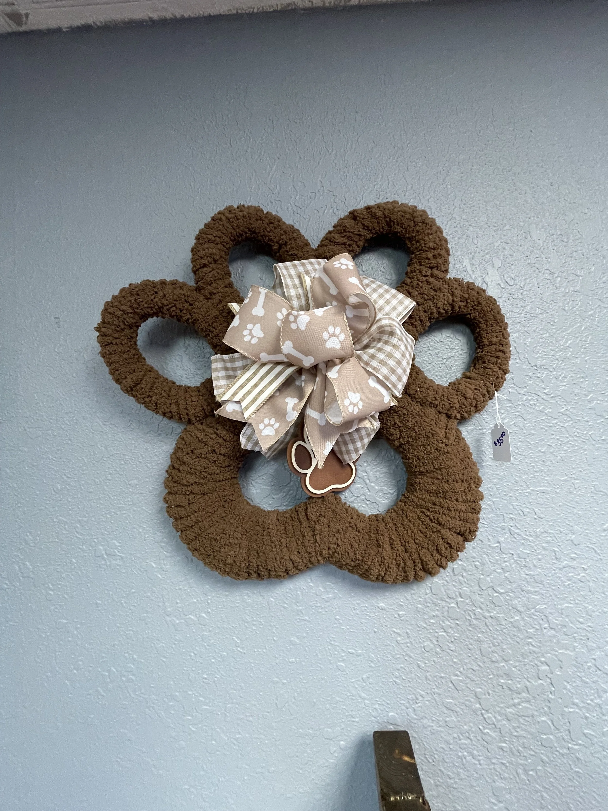 An image of a paw print shaped wreath made by Chris Kelly hanging on a wall