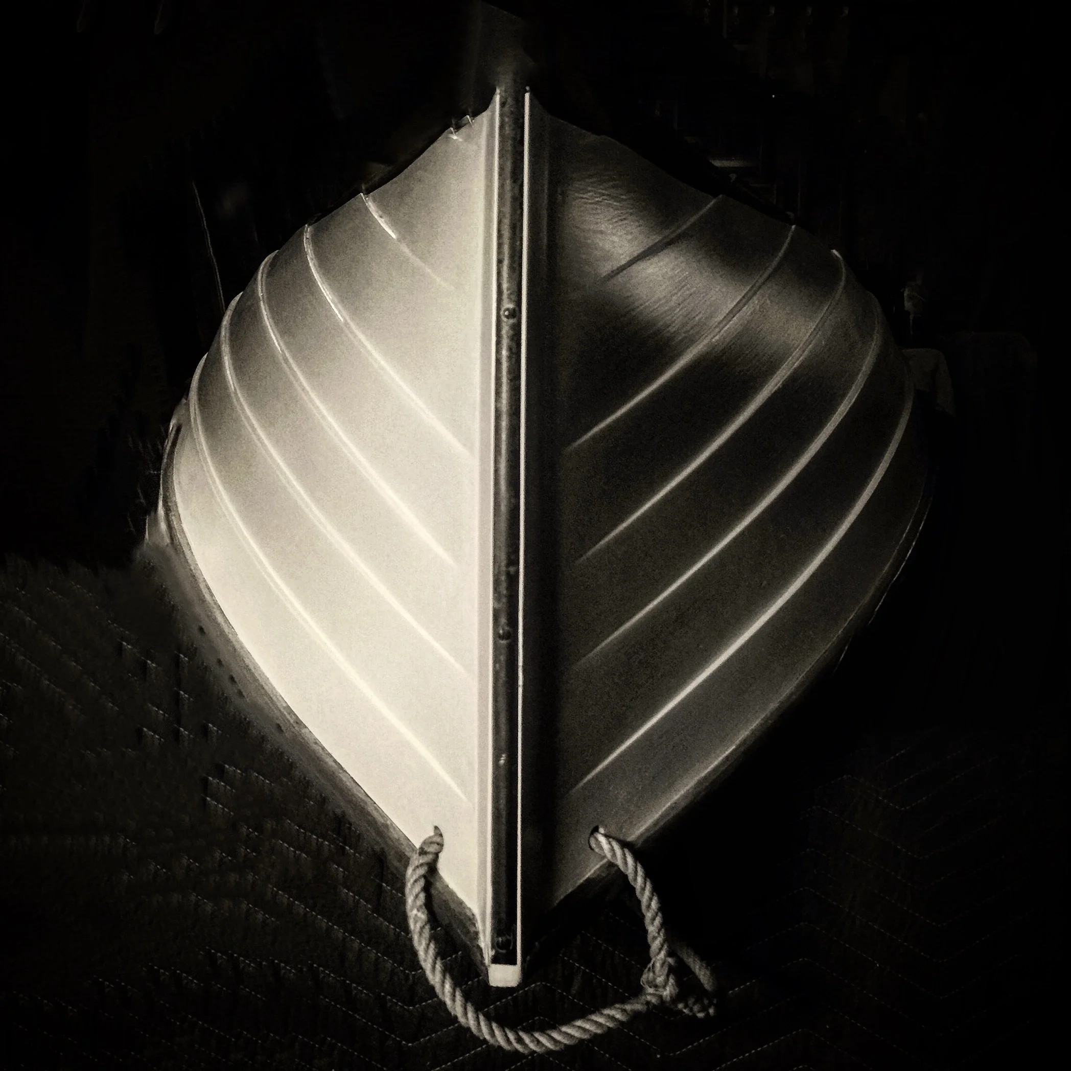 A black and white photo of a canoe turned upside down