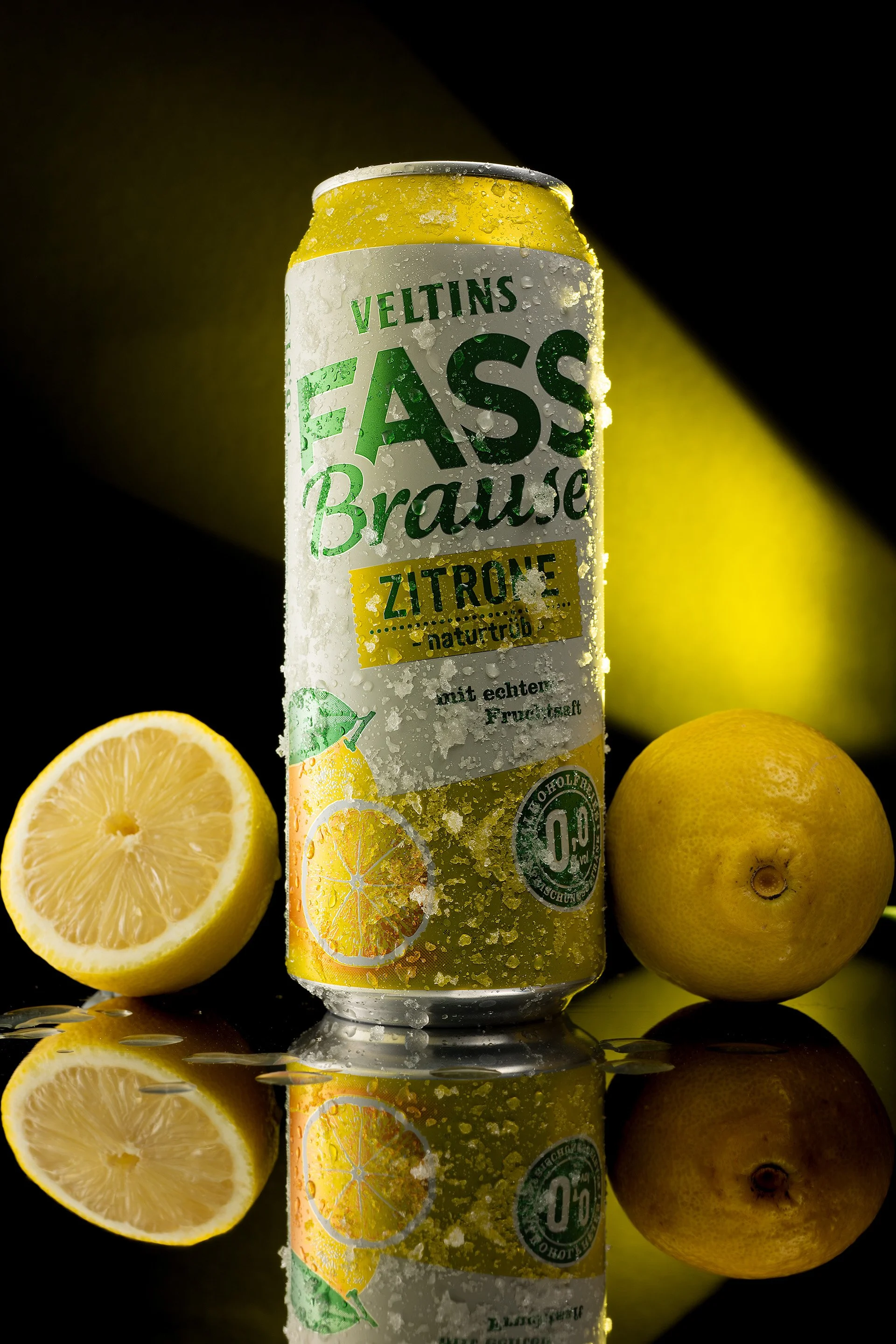 Erfrischungsgetränk Produktfotografie, Veltins Fassbrause Zitrone Dose mit Wassertropfen, frische Zitronen auf spiegelndem Untergrund, Food & Beverage Fotografie mit technischer Lichtführung.