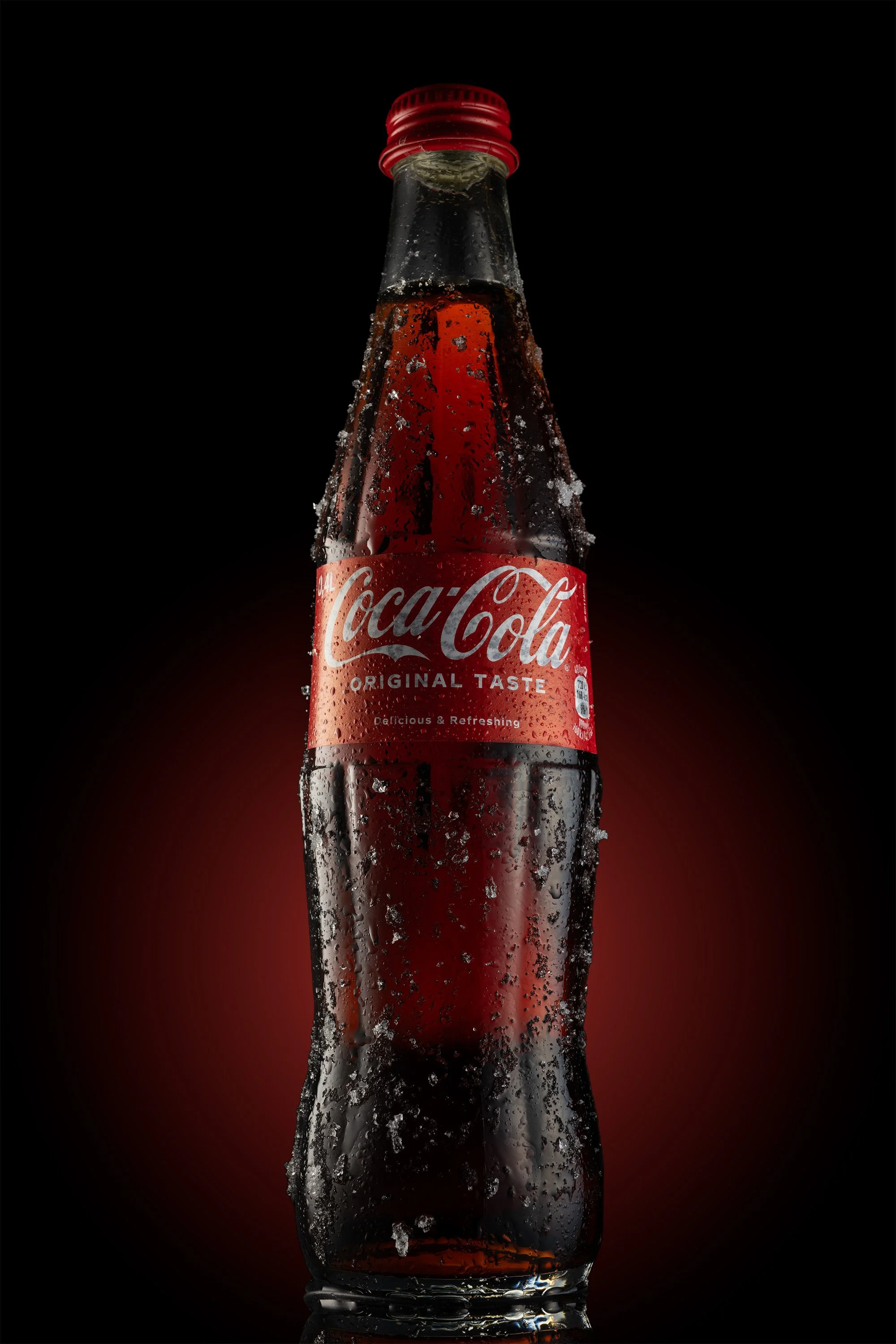 Professionelle Produktfotografie Coca-Cola Glasflasche mit Eis- und Frosteffekt, dramatisches Gegenlicht auf dunklem Grund mit rotem Glow, technischer Clean-Shot für Erfrischungsgetränke.
