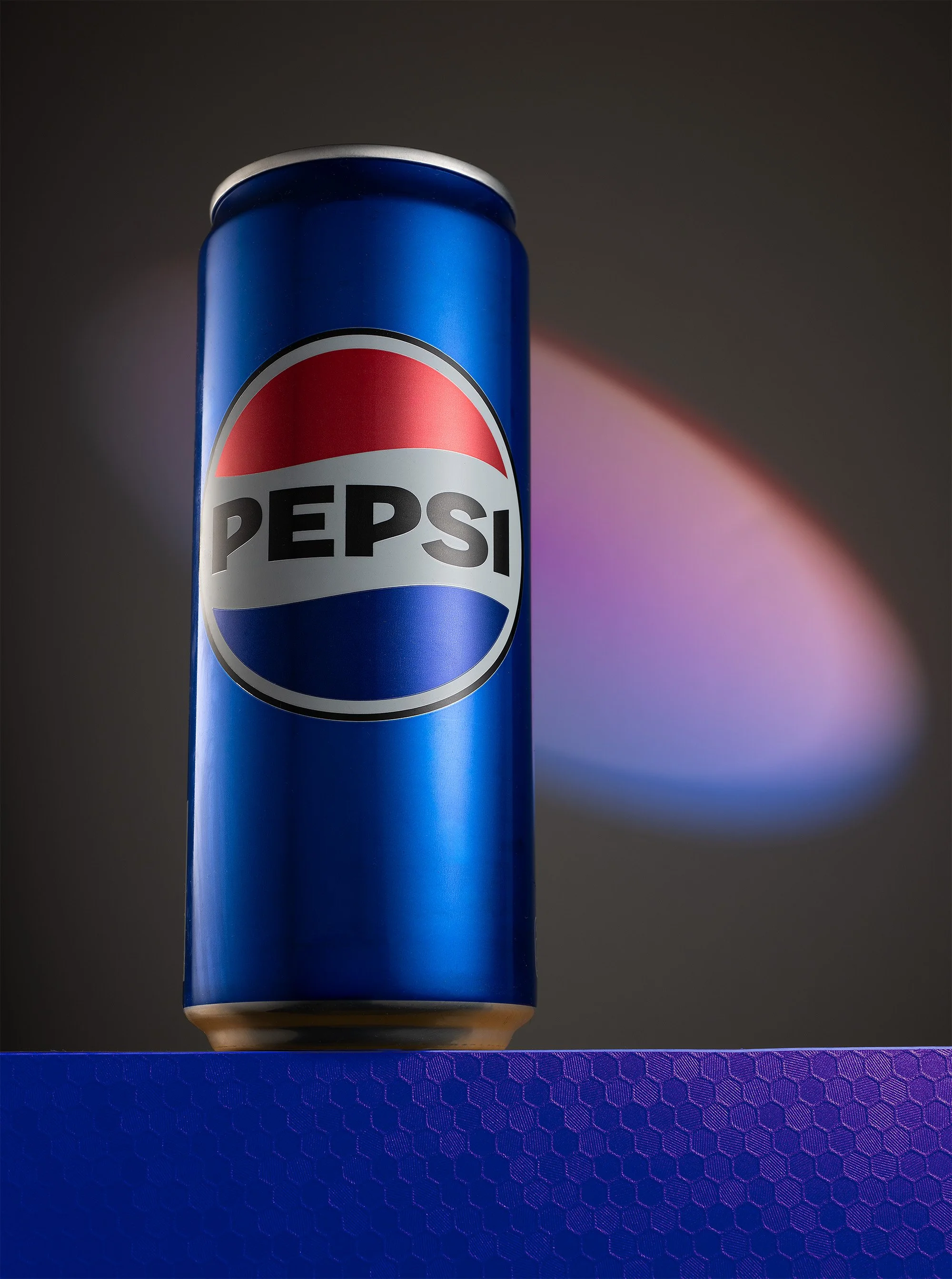 Professionelle Getränkefotografie, Pepsi-Dose in Blau auf strukturiertem Untergrund, präzise Lichtkanten und grafische Lichteffekte im Hintergrund, technischer Clean-Shot für Product-Placement.