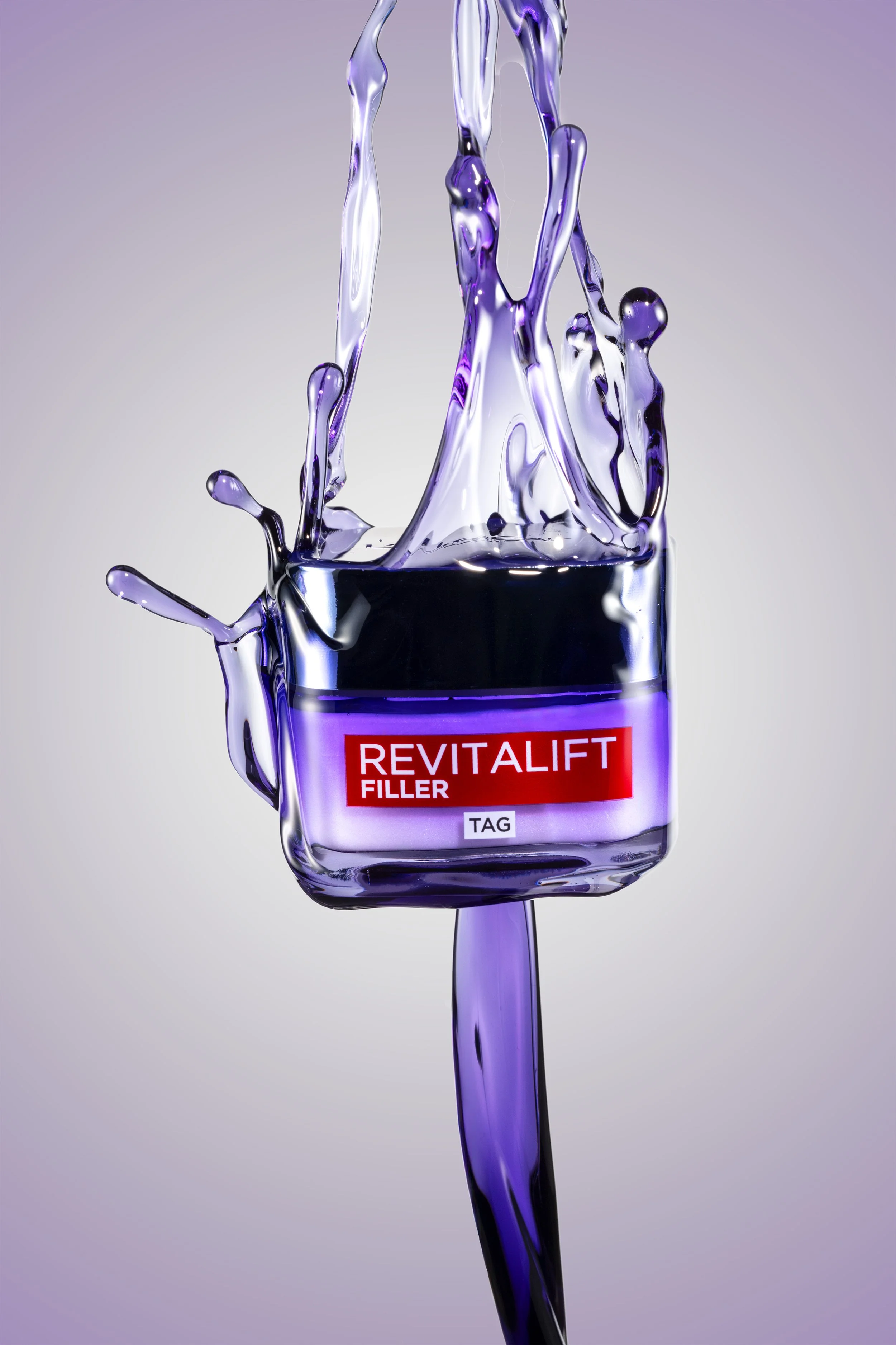 Professionelle Kosmetikfotografie, L'Oréal Revitalift Filler Tagespflege mit dynamischem Wasser-Splash, violette Lichtstimmung, High-Speed-Fotografie für Beauty-Produkte.