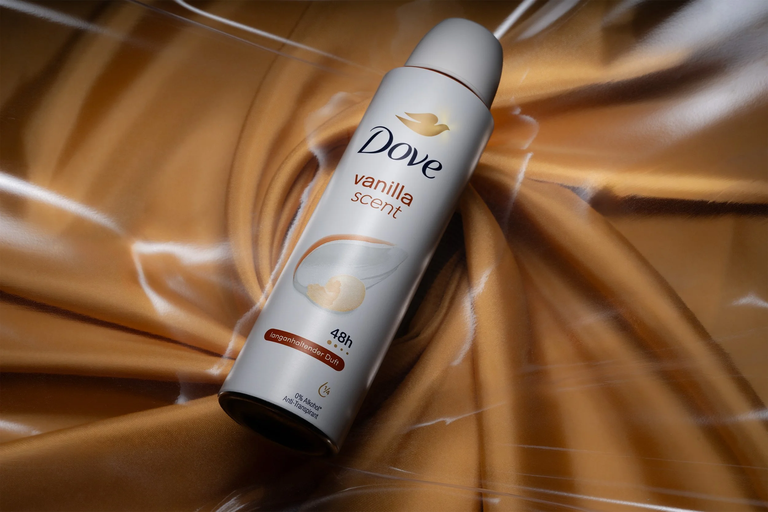 Professionelle Produktfotografie Dove Deo Spray Vanilla Scent, Inszenierung auf goldenem Seidenstoff, weiche Lichtführung, technischer Clean-Shot für Beauty- und Pflegeprodukte.