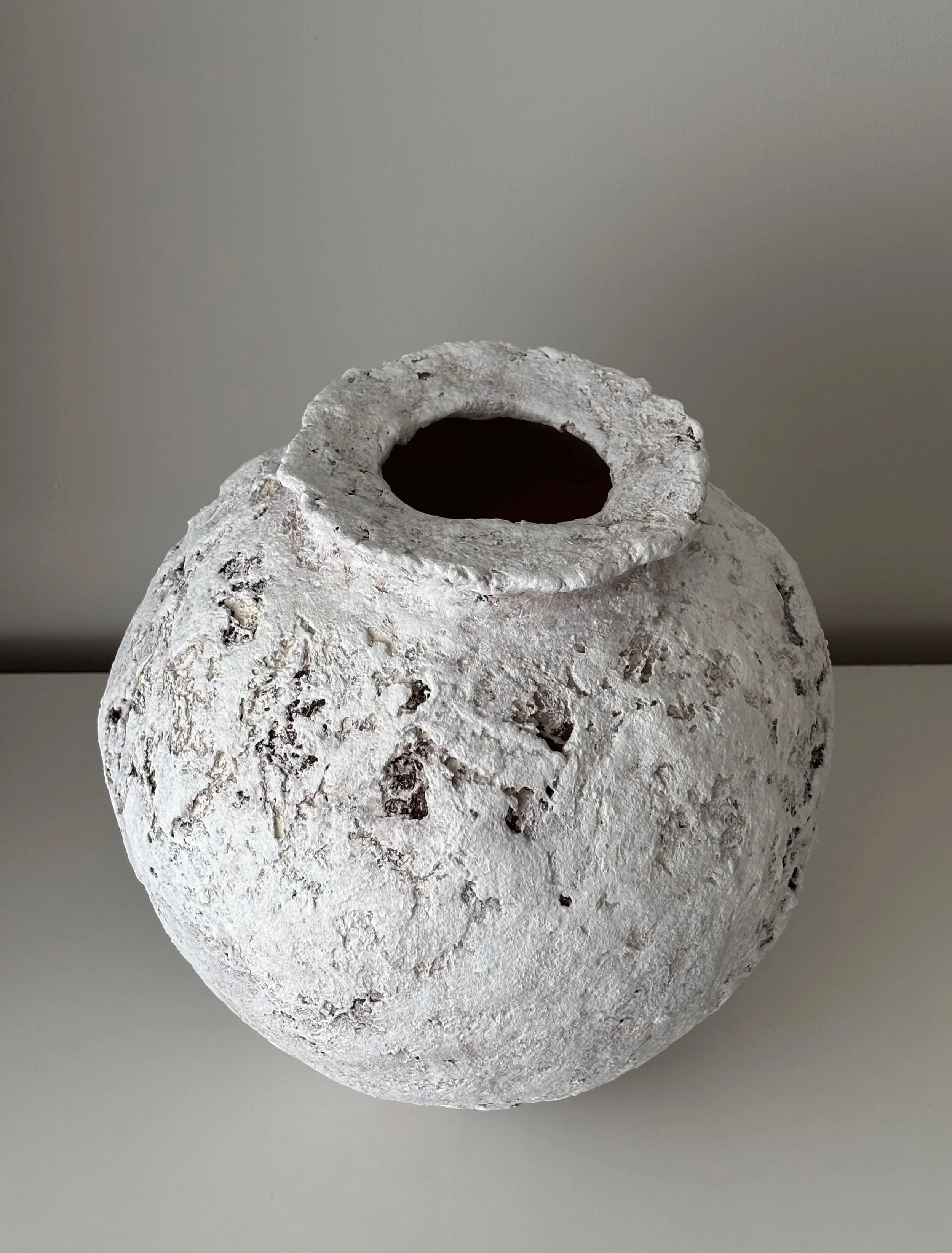 Wabi Sabi Textured Vessel N.49, off-white paper clay vessel viewed from an alternate angle highlighting asymmetrical shape, from Papier Atelier London